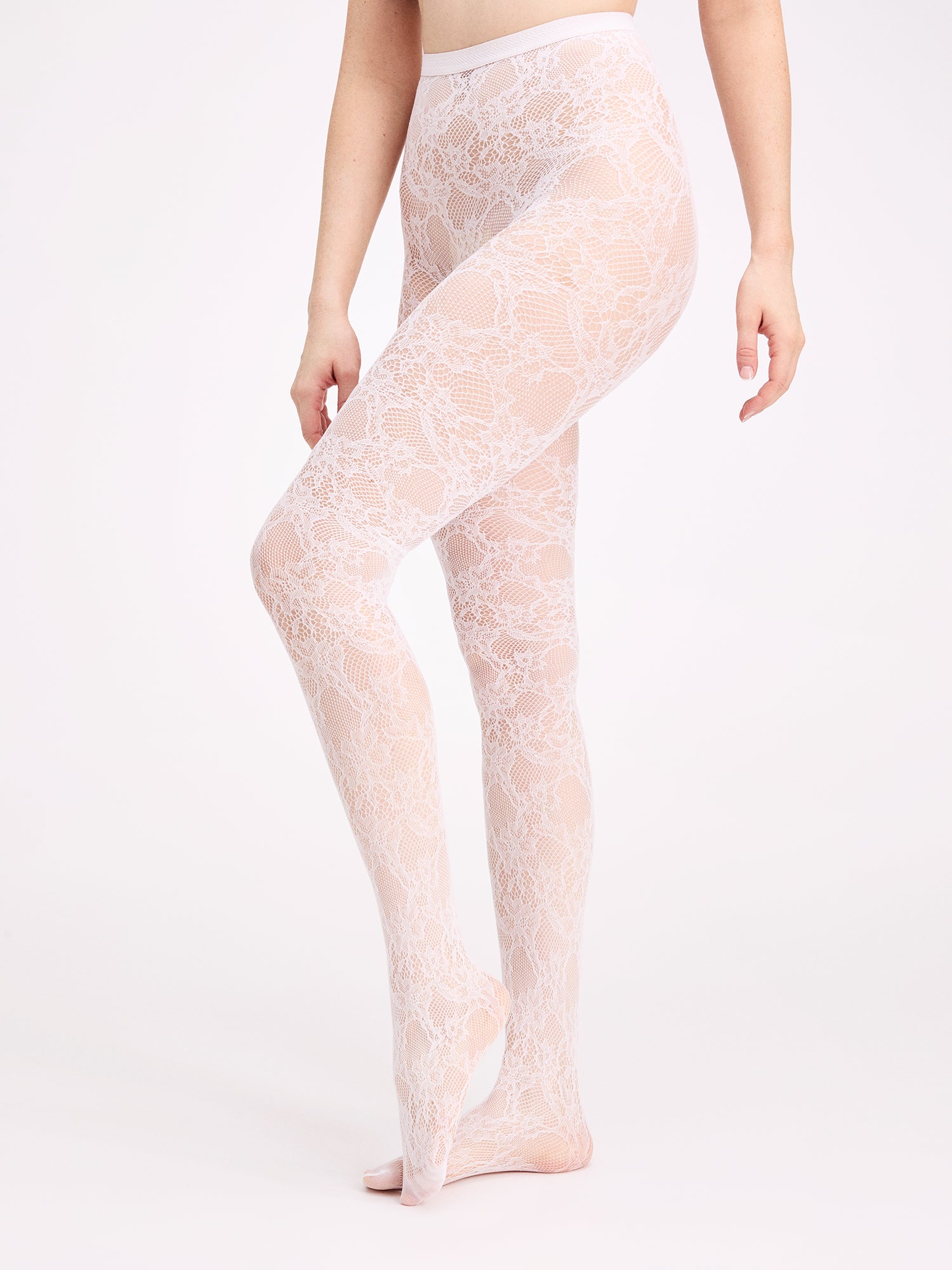 Voguen trendikkäät 60 denierin pitsisukkahousut valkoisena. Sukkahousuissa on rajaton housuosa ja vahvistettu kärki. Kuvassa mallin päällä sivusta kuvattuna.