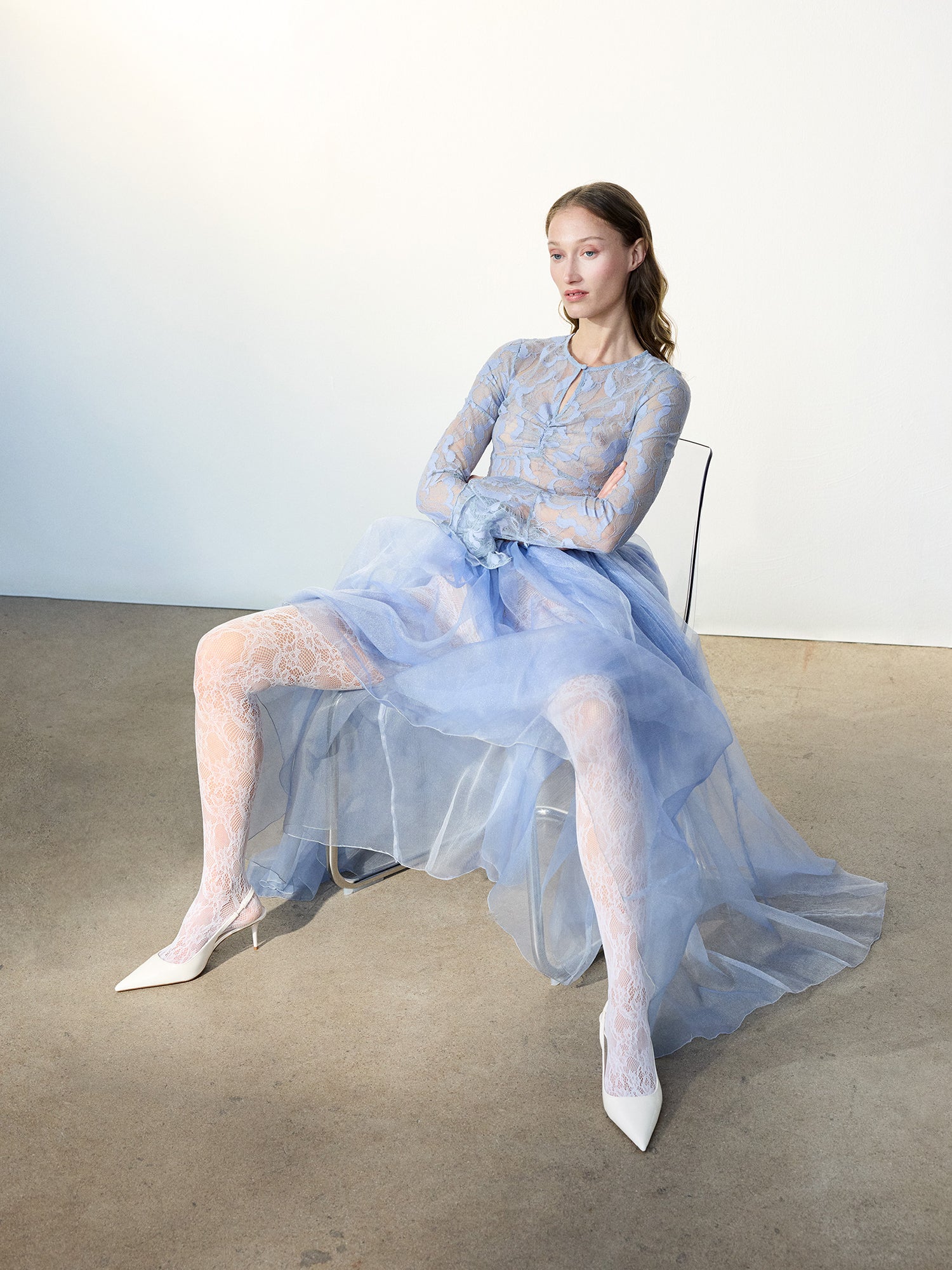 Voguen trendikkäät 60 denierin pitsisukkahousut valkoisena. Sukkahousuissa on rajaton housuosa ja vahvistettu kärki. Brändikuvassa mallin päällä vaaleansinisen sifonki-pitsimekon kanssa. Jalassa mallilla on valkoiset korkokengät.