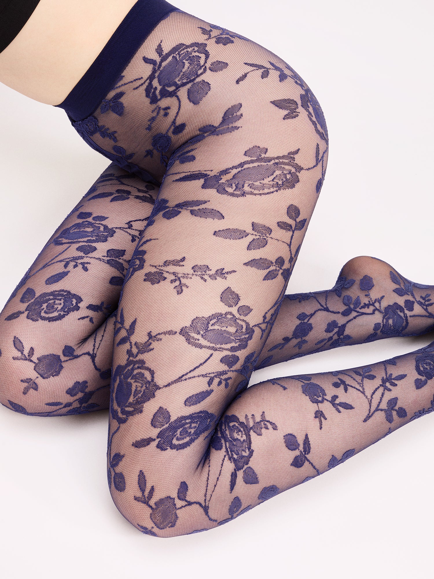 Voguen kauniit 30 denierin kukkakuviolliset sukkahousut sinisenä rajattomalla housuosalla. Lähikuvassa mallin päällä sivusta kuvattuna.