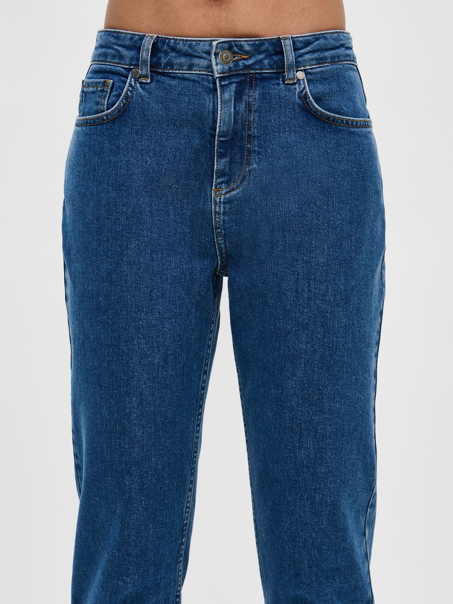 Nanson naisten mukavat ja vajaamittaiset siniset Fiilis-farkut lähikuvana edestä. Näkyvissä vyötärö, nappi ja vetoketju.