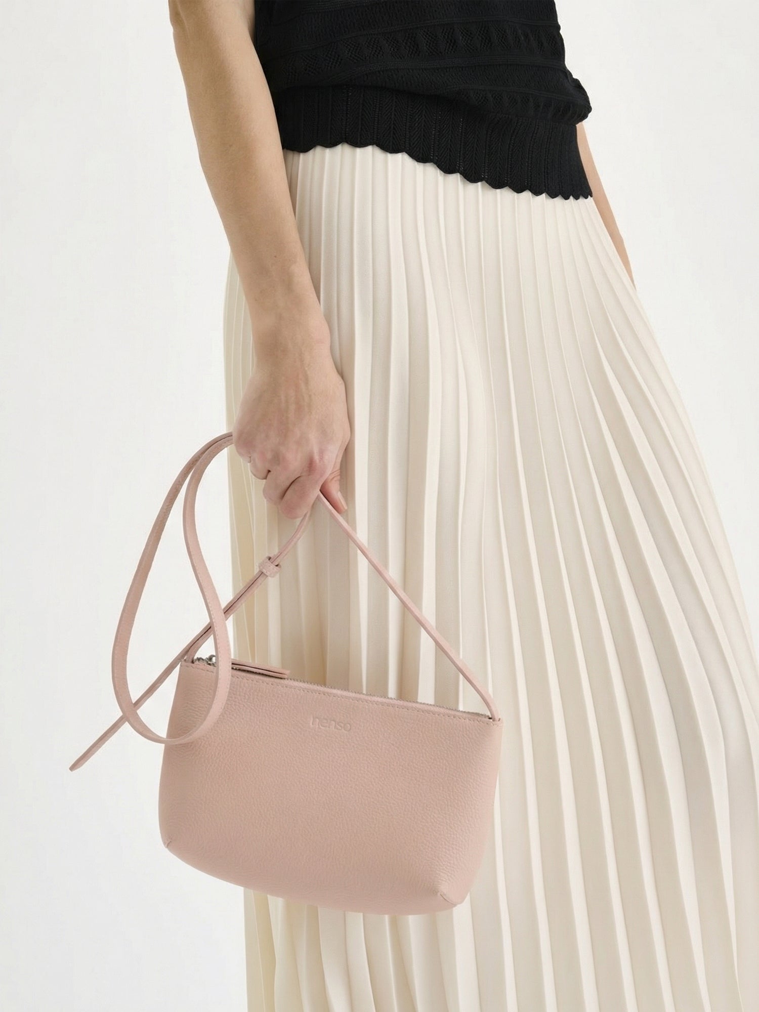 Nanson tyylikäs vaaleanpunainen Naru- olkalaukku. Upea ja käytännöllinen crossbody- tyylinen nahkalaukku arkeen ja juhlaan. Nahkalaukussa on pitkä säädettävä olkahihna ja vetoketju kiinnitys. Tuote on valmistettu sertifioidusta nahasta. Kuvassa mallin kädessä vekkihameen kanssa.