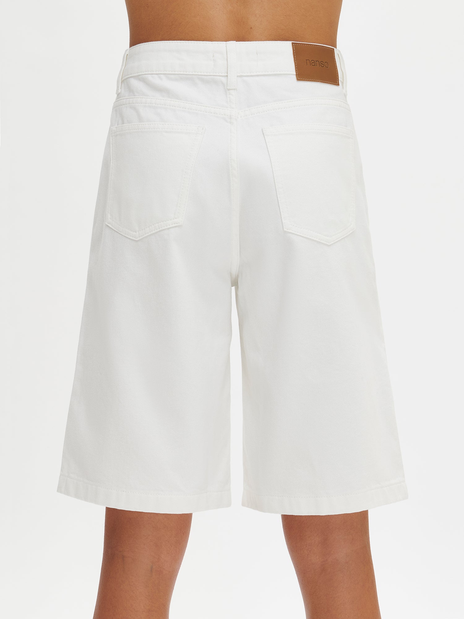 Nanson naisten mukavat rennosti istuvat luonnonvalkoiset Levee-shortsit farkkumateriaalista vyötärökaitaleella, jossa edessä vetoketju ja polviin asti ulottuvat levenevät lahkeet  mallin yllä lähikuvassa takaa.