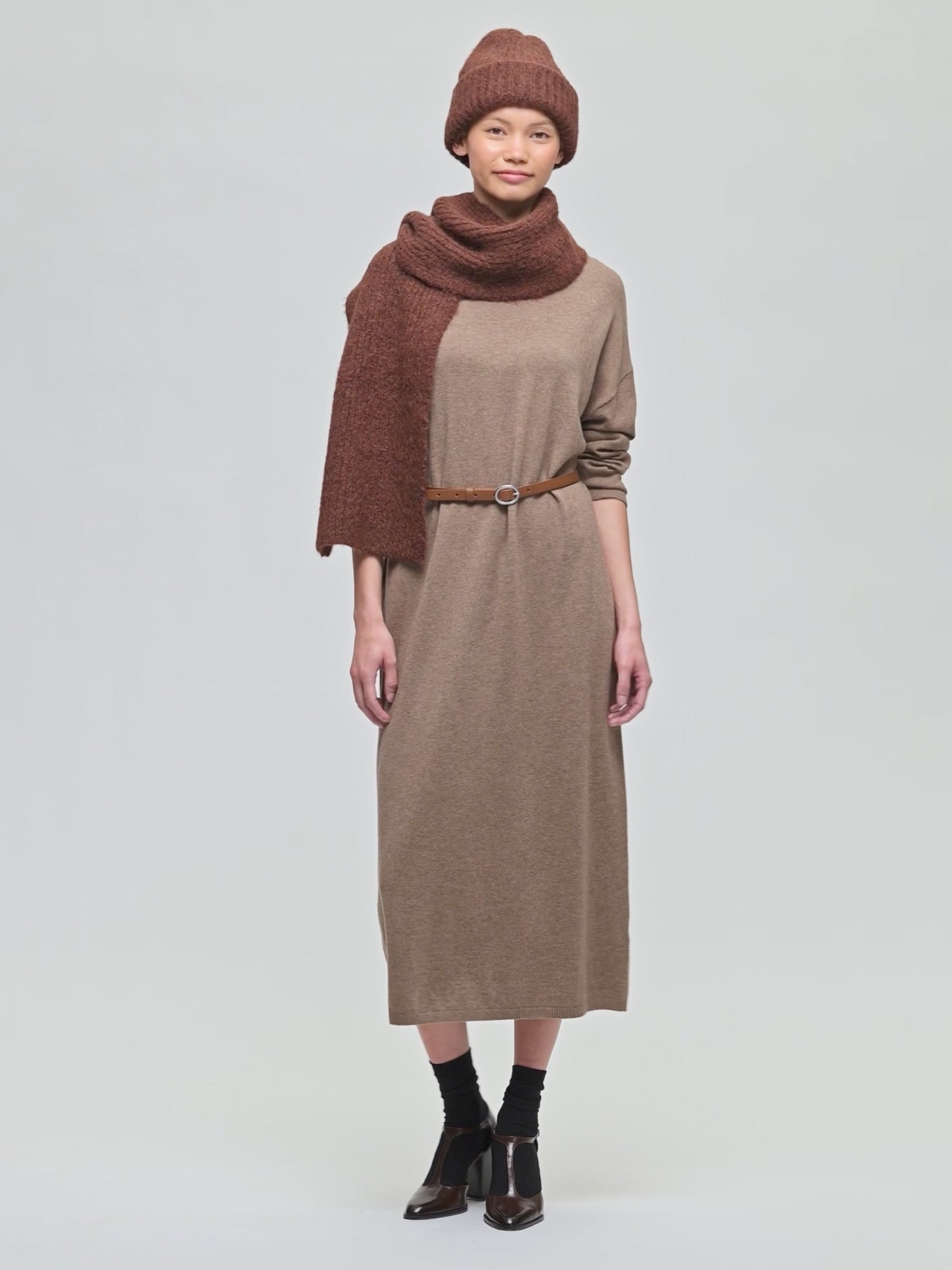 Nanso pitkä beige Villis-mekko mallilla. Asusteina ruskea vyö ja Utu-pipo sekä kaulahuivi.