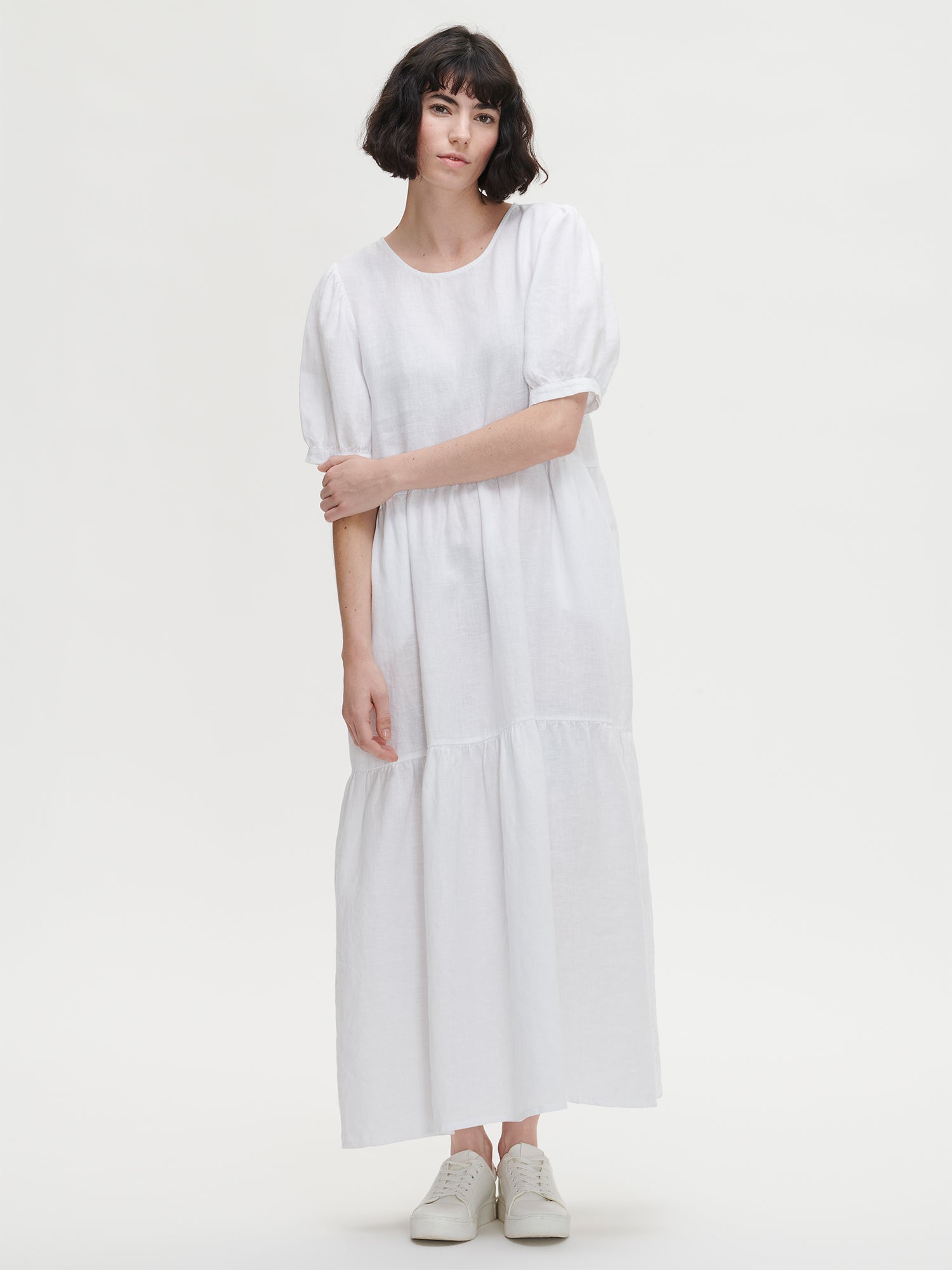 Nanson naisten kaunis valkoinen Sarastus-mekko volyymisilla frillakerroksilla ja lyhyillä puhvihihoilla, joissa on napit säätövaralla. 