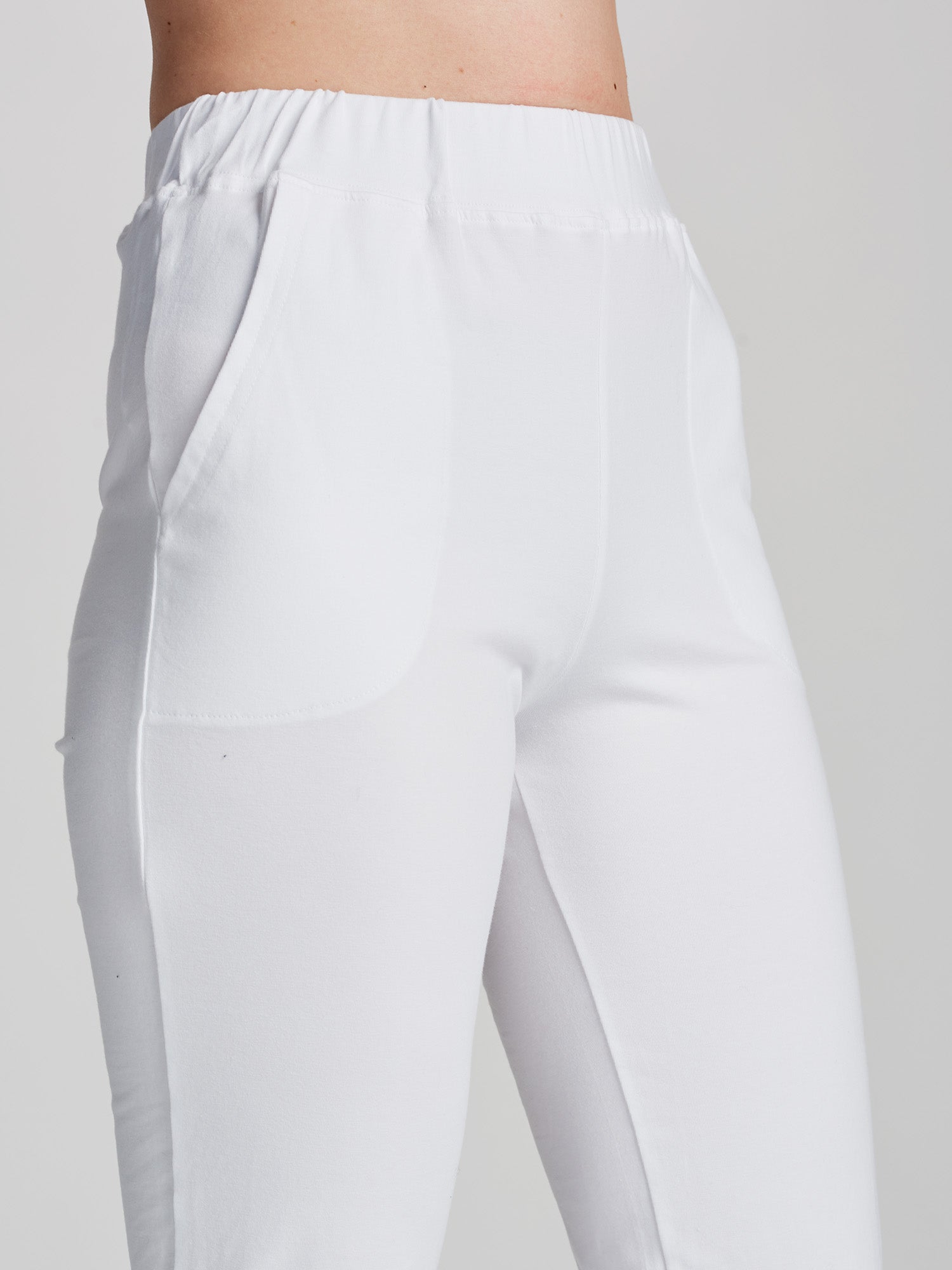 Nanson naisten joustavat ja mukavat valkoiset Basic-trikoohousut lahkeen halkiolla ja kuminauhavyötäröllä sivulta lähikuvassa.
