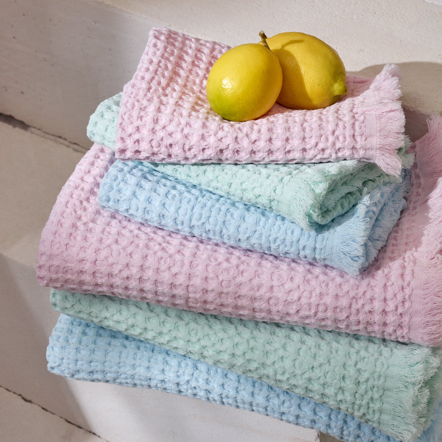 Nanson pastellisävyiset Vohveli-pyyhkeet pinossa hedelmien kanssa.