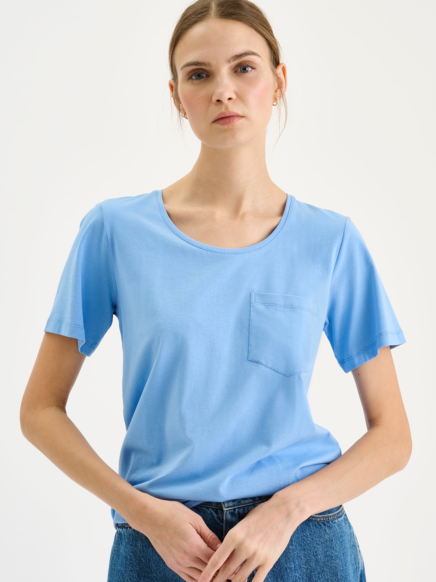 Nanson naisten vaaleansininen Tasku-t-paita pyöreällä pääntiellä mallin päällä farkkushortsien kanssa lähikuvassa