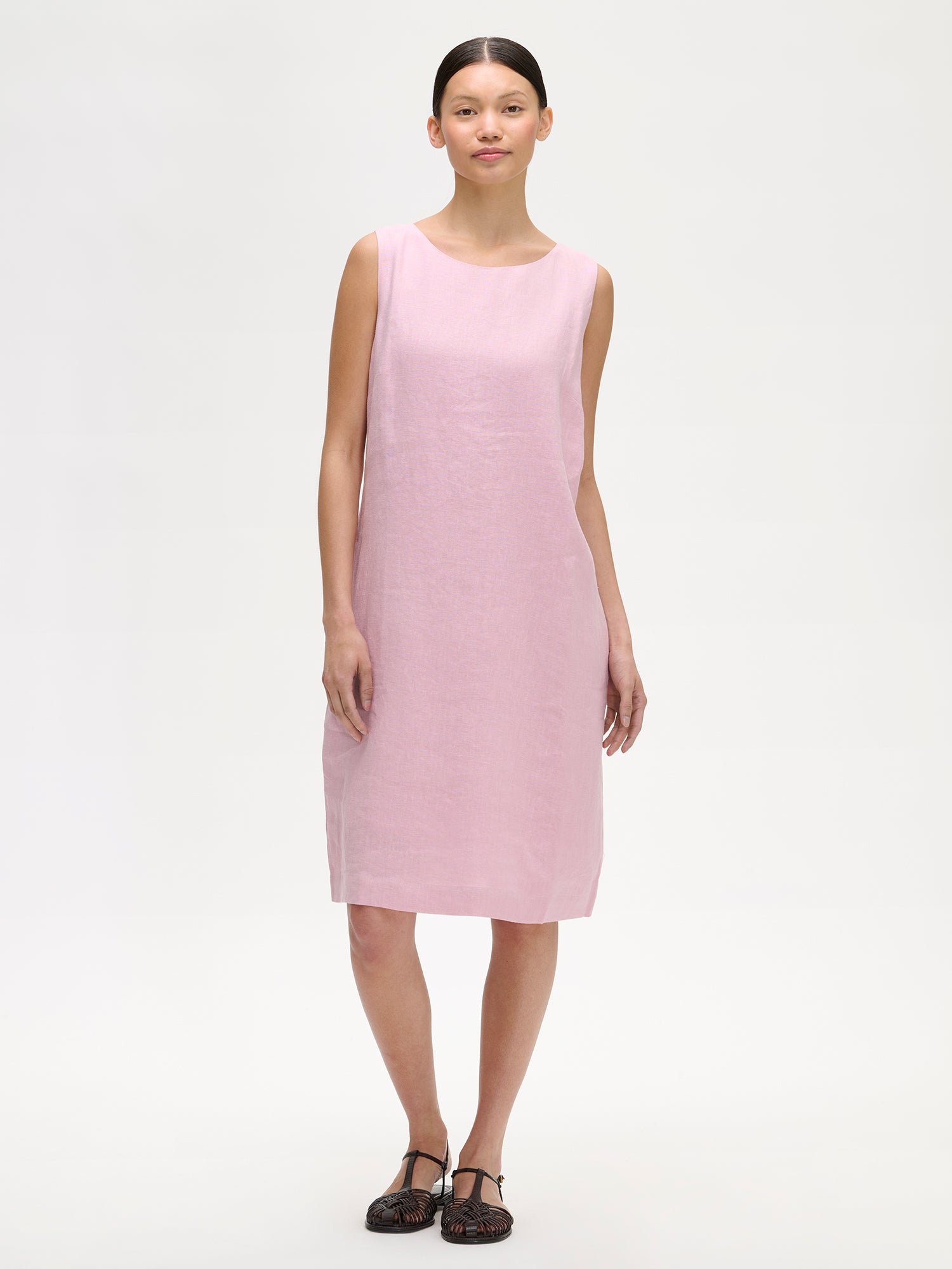 Nanson naisten hihaton roosa Luoto-pellavamekko mallin päällä sandaalien kanssa.