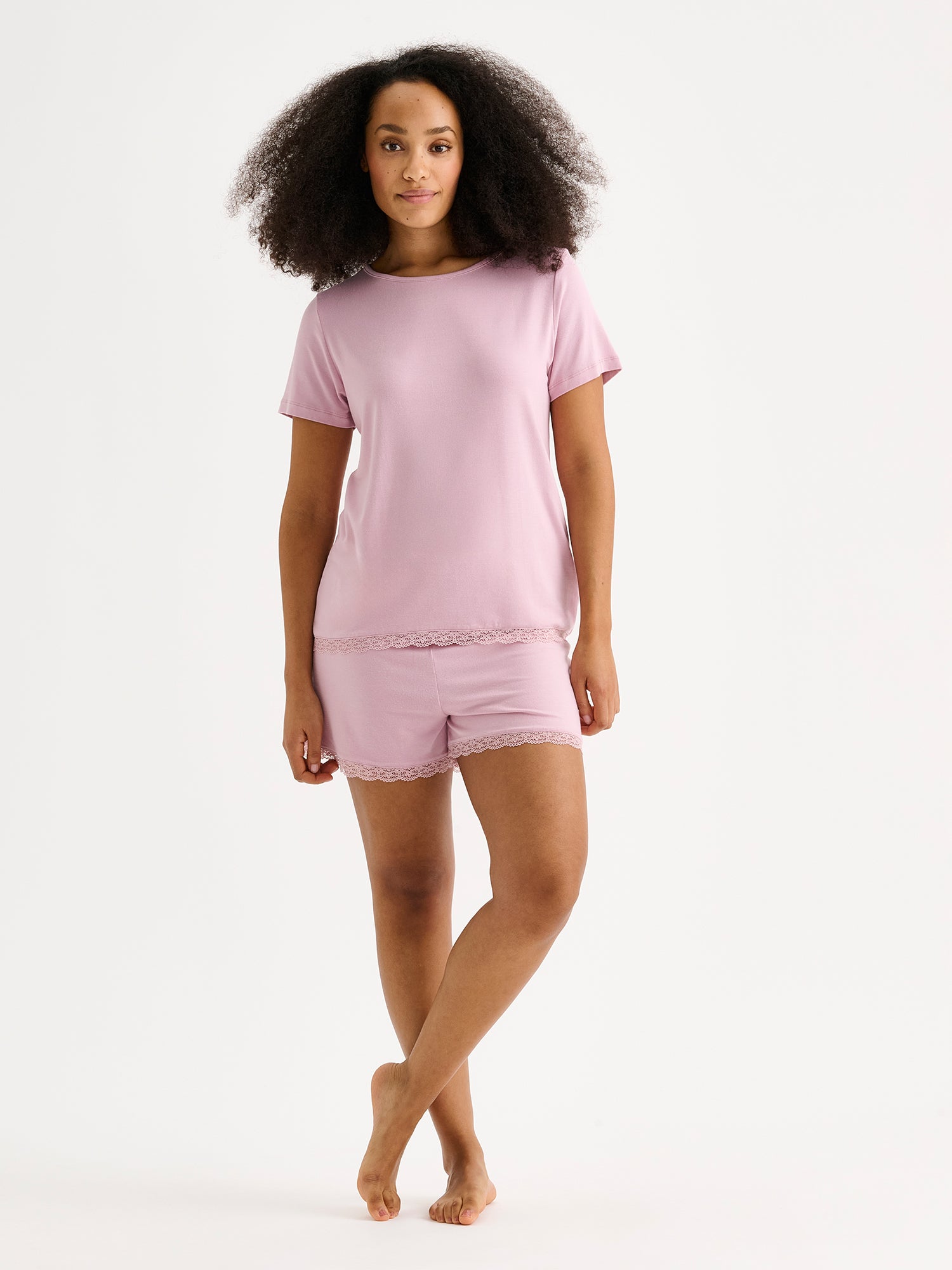 Naisten ylellisen pehmeä vaaleanpunainen Pitsi-pusero lyhyillä hihoilla mallin päällä Pitsi -shortsien kanssa.