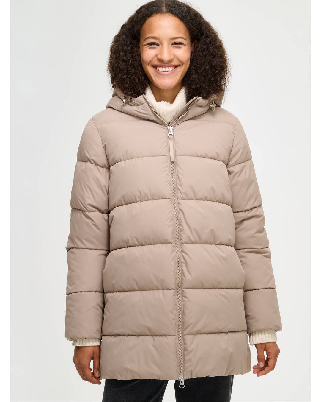 Lämmin ja muhkea beige Lumi-toppatakki miellyttävän kevyellä vanuvuorella. Mallin päällä edestä läheltä.
