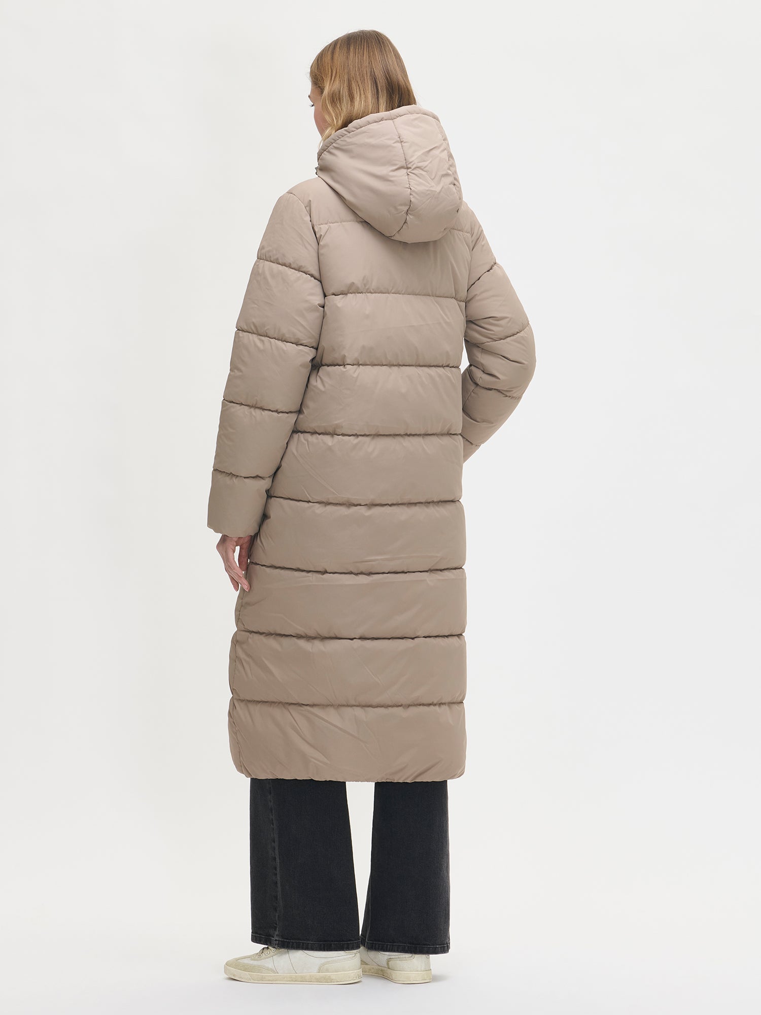Lämmin ja muhkea pitkä beige Lumi-toppatakki miellyttävän kevyellä vanuvuorella. Mallin päällä takaa.