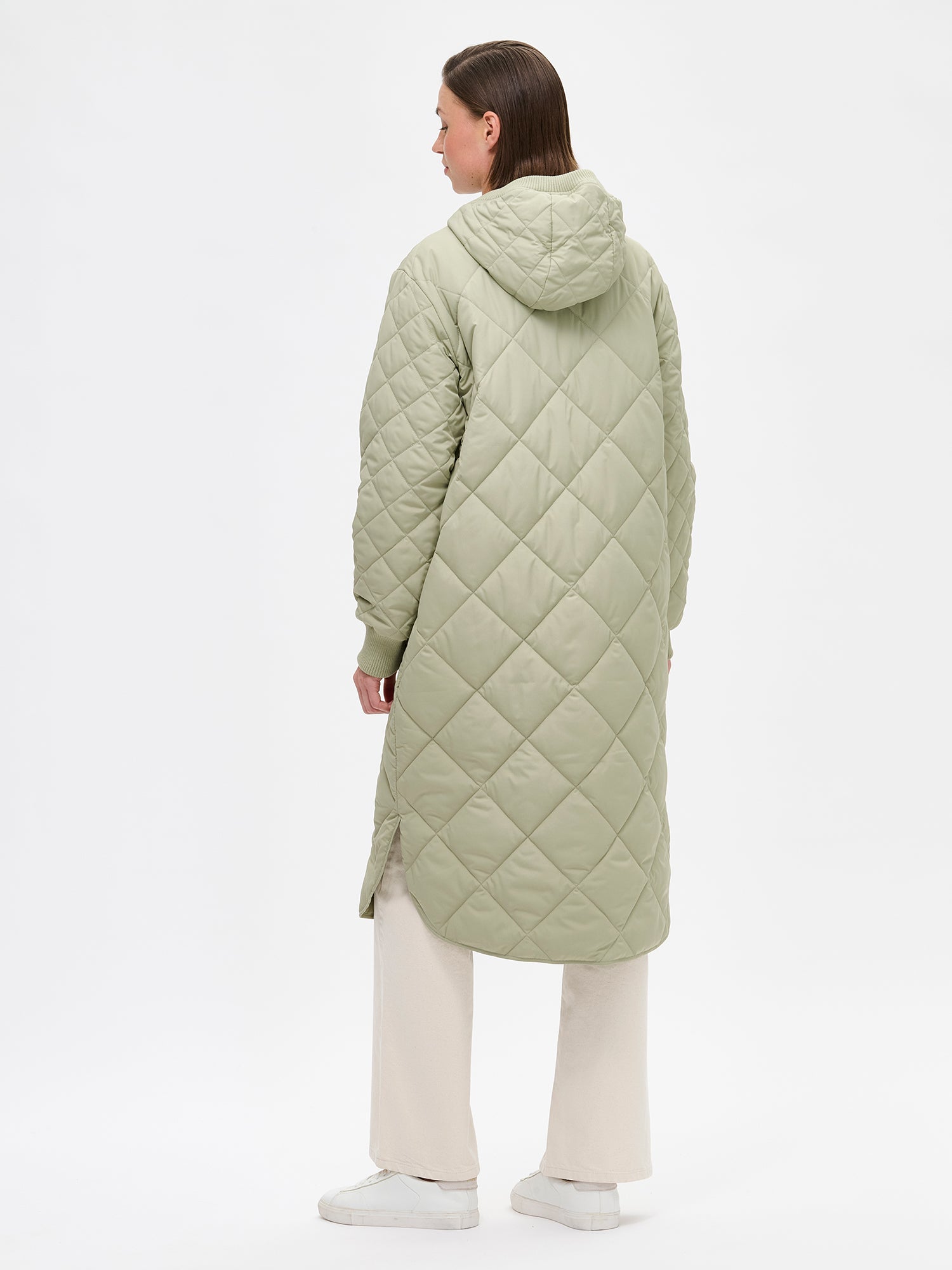 Nanson naisten rennon tyylikäs vihreä Maxi Hood-tikkitakki kevyellä vanulla ja lämpimällä hupulla. Hupullinen tikkitakki on täydellinen valinta välikauteen. Kuvassa mallin päällä takaa kuvattuna.