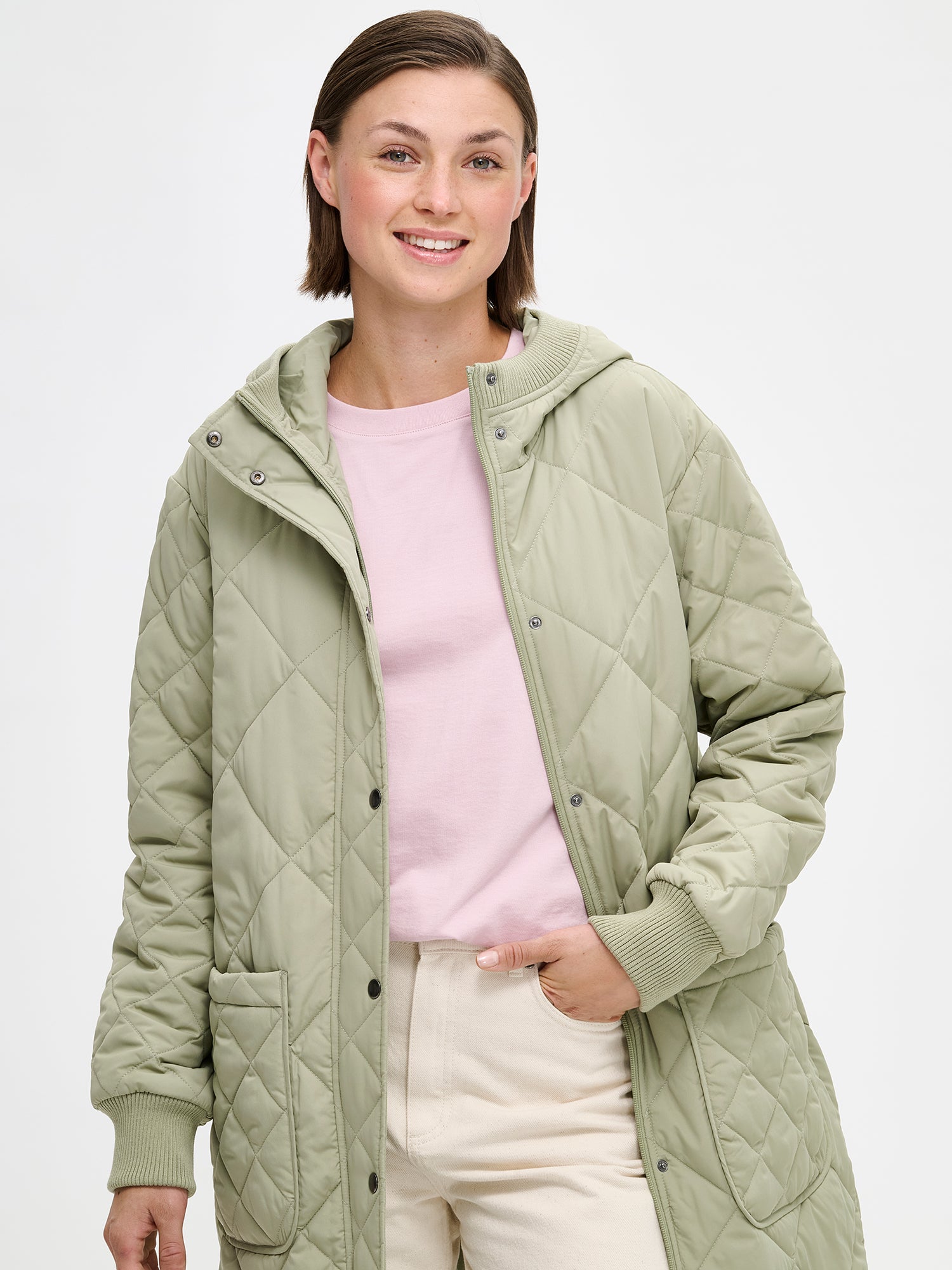 Nanson naisten rennon tyylikäs vihreä Maxi Hood-tikkitakki kevyellä vanulla ja lämpimällä hupulla. Hupullinen tikkitakki on täydellinen valinta välikauteen. Kuvassa mallin päällä läheltä kuvattuna, takki auki.