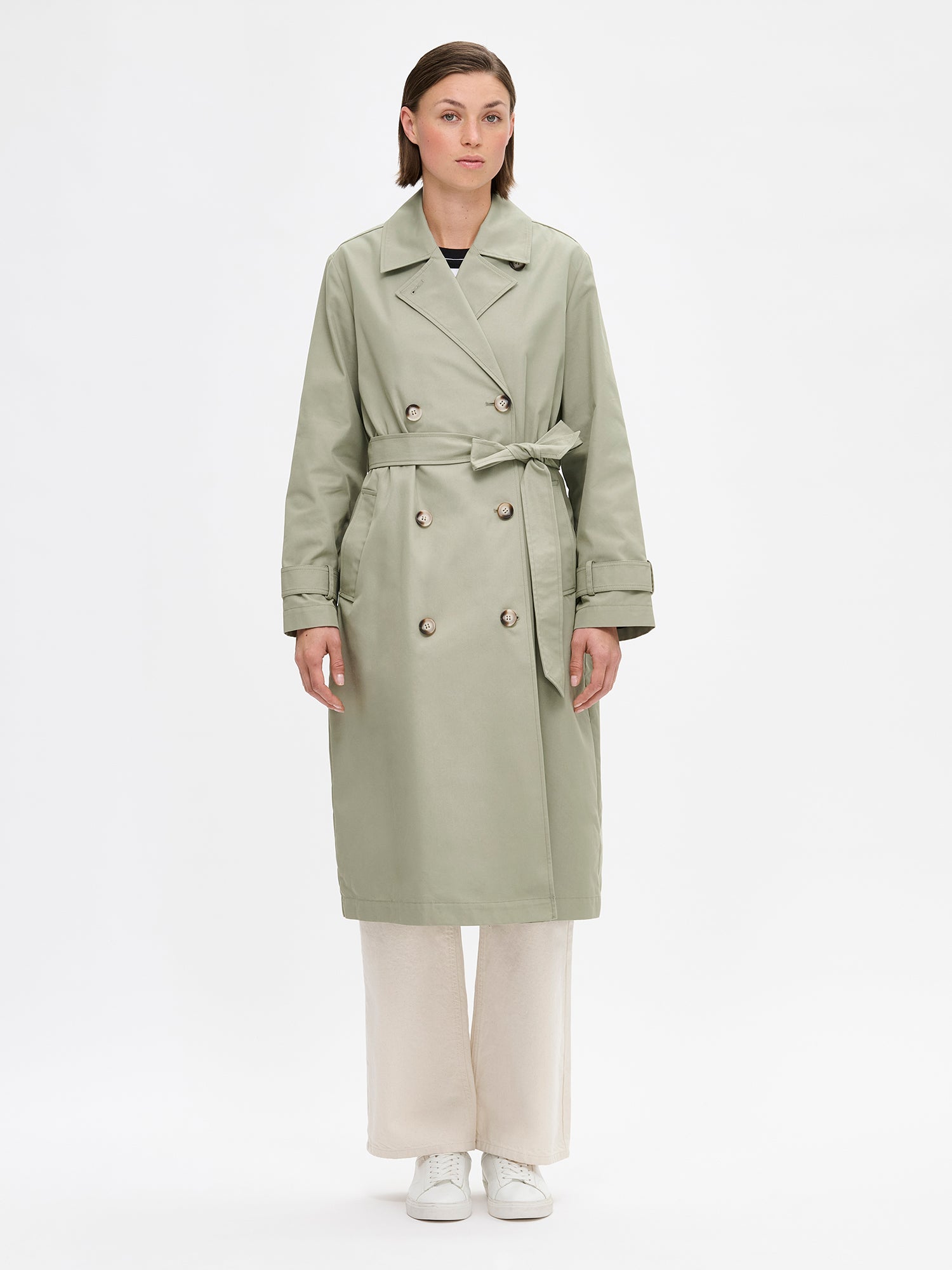 Nanson naisten klassisen tyylikäs vaaleanvihreä Trenssi-takki mallin päällä vaaleiden farkkujen kanssa.