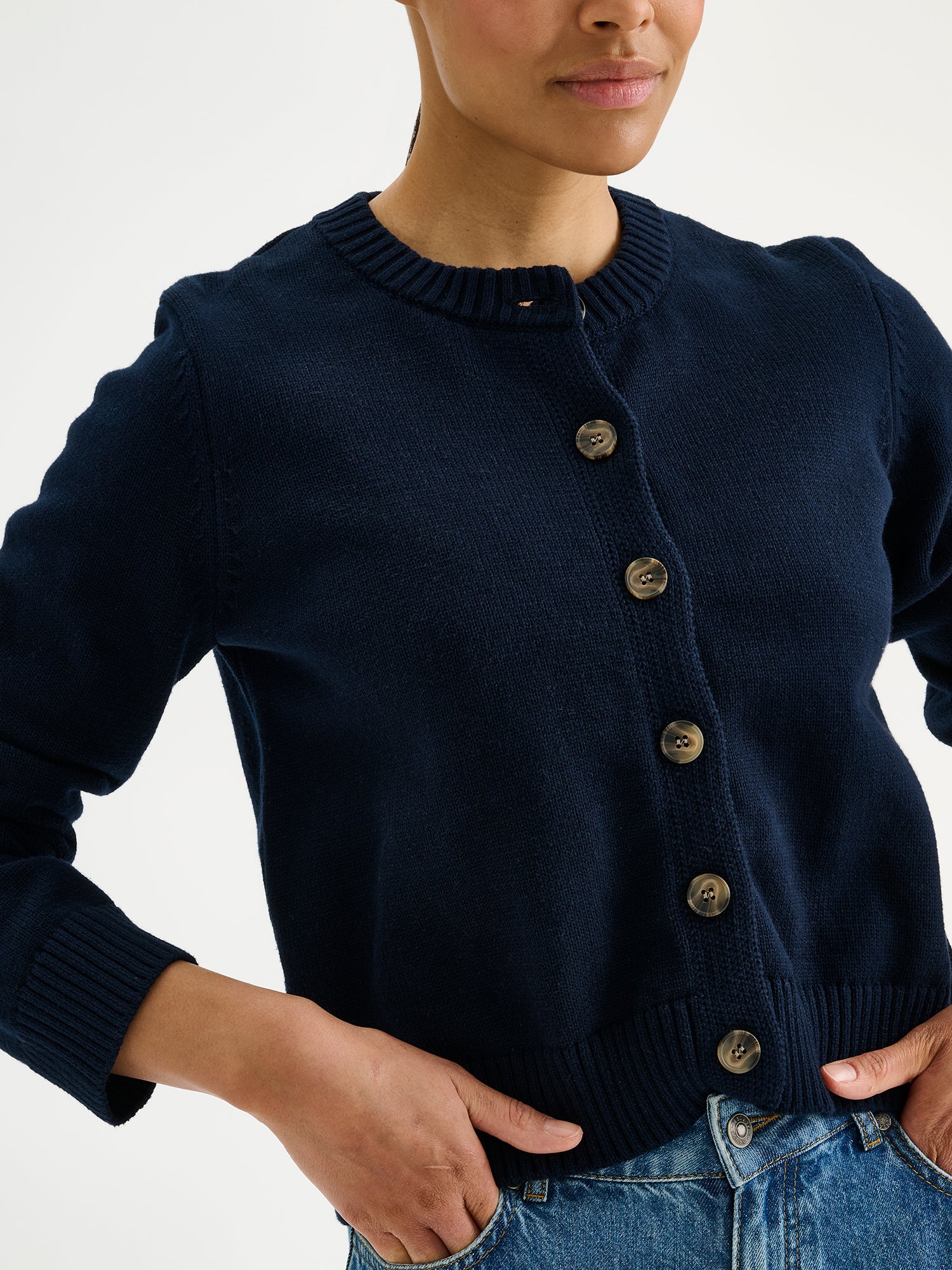 Nanson naisten pitkähihainen ja suoralinjainen tummansininen Mira-neuletakki mallin päällä Rento-farkkujen kanssa lähikuvassa.