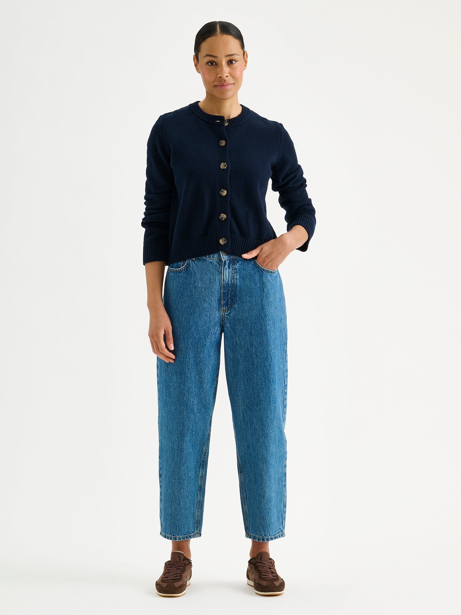 Nanson naisten pitkähihainen ja suoralinjainen tummansininen Mira-neuletakki mallin päällä Rento-farkkujen kanssa.