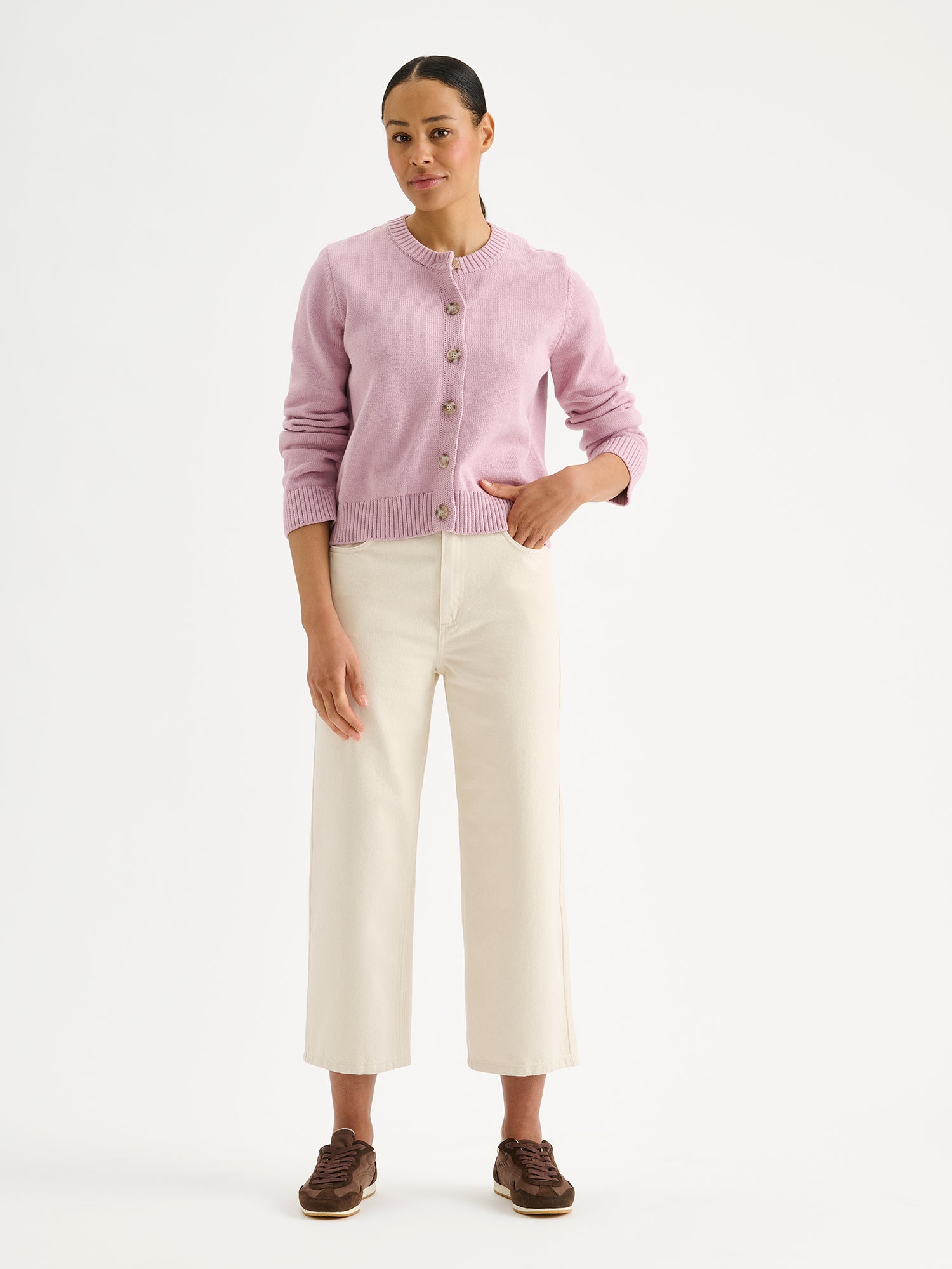 Nanson naisten pitkähihainen ja suoralinjainen roosa Mira-neuletakki mallin päällä luonnonvalkoisten farkkujen kanssa.