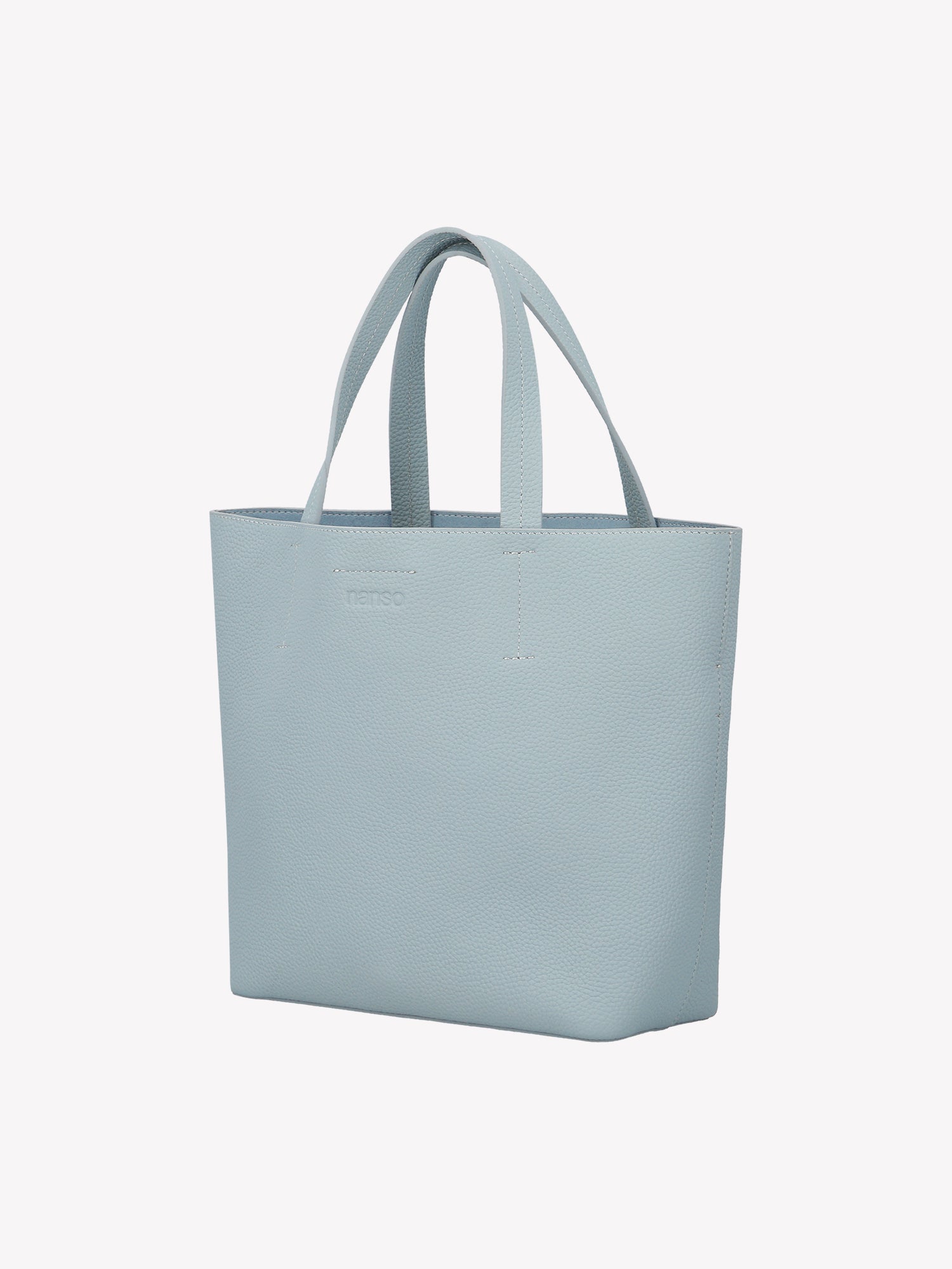 Nanson tyylikäs vaaleansininen Naru Tote- nahkalaukku. Naru Tote -nahkalaukussa on sekä lyhyemmät kantohihnat että pidempi irrotettava ja säädettävä olkahihna. Tuote on valmistettu sertifioidusta nahasta. Tuotekuva edestä, ilman crossbody -hihnaa.