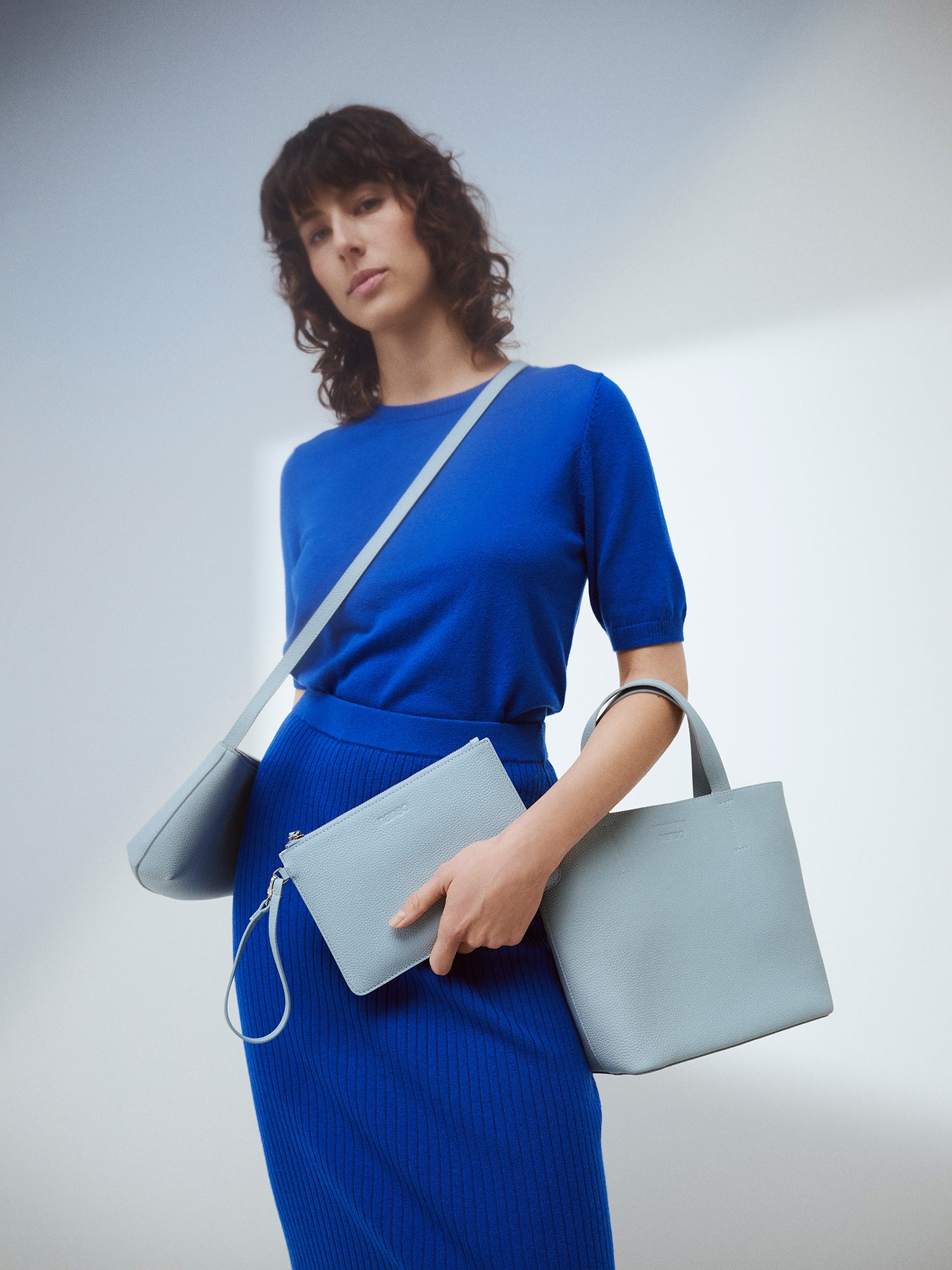 Nanson tyylikäs vaaleansininen Naru Tote- nahkalaukku. Naru Tote -nahkalaukussa on sekä lyhyemmät kantohihnat että pidempi irrotettava ja säädettävä olkahihna. Tuote on valmistettu sertifioidusta nahasta. Brändikuva mallin kanssa, jossa sininen asu ja 3 narulaukkua.