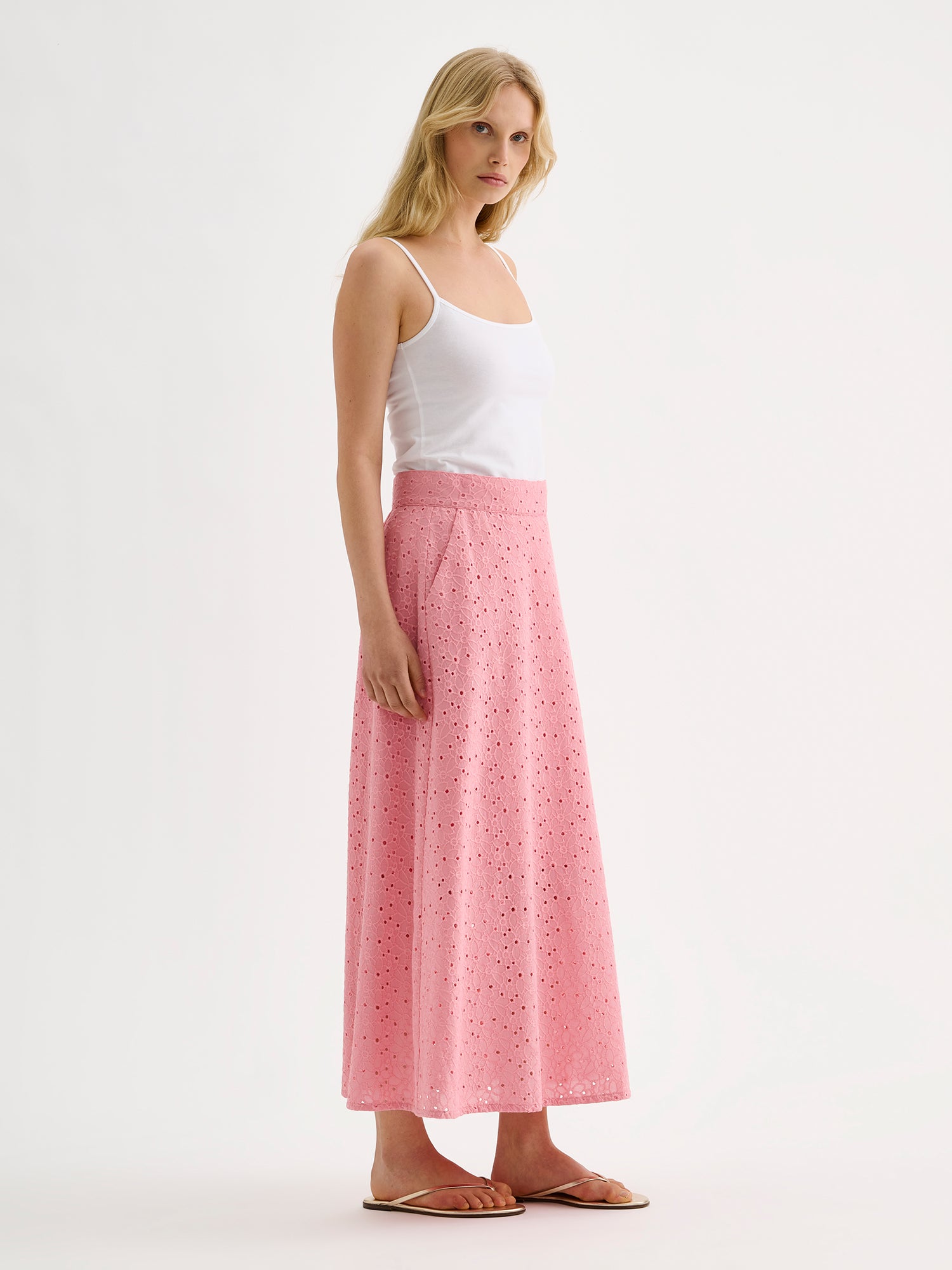 Nanson naisten vaaleanpunainen brodeerattu Nuppu-hame mallin päällä valkoisen naruolkaimisen topin kanssa sivusta kuvattuna.