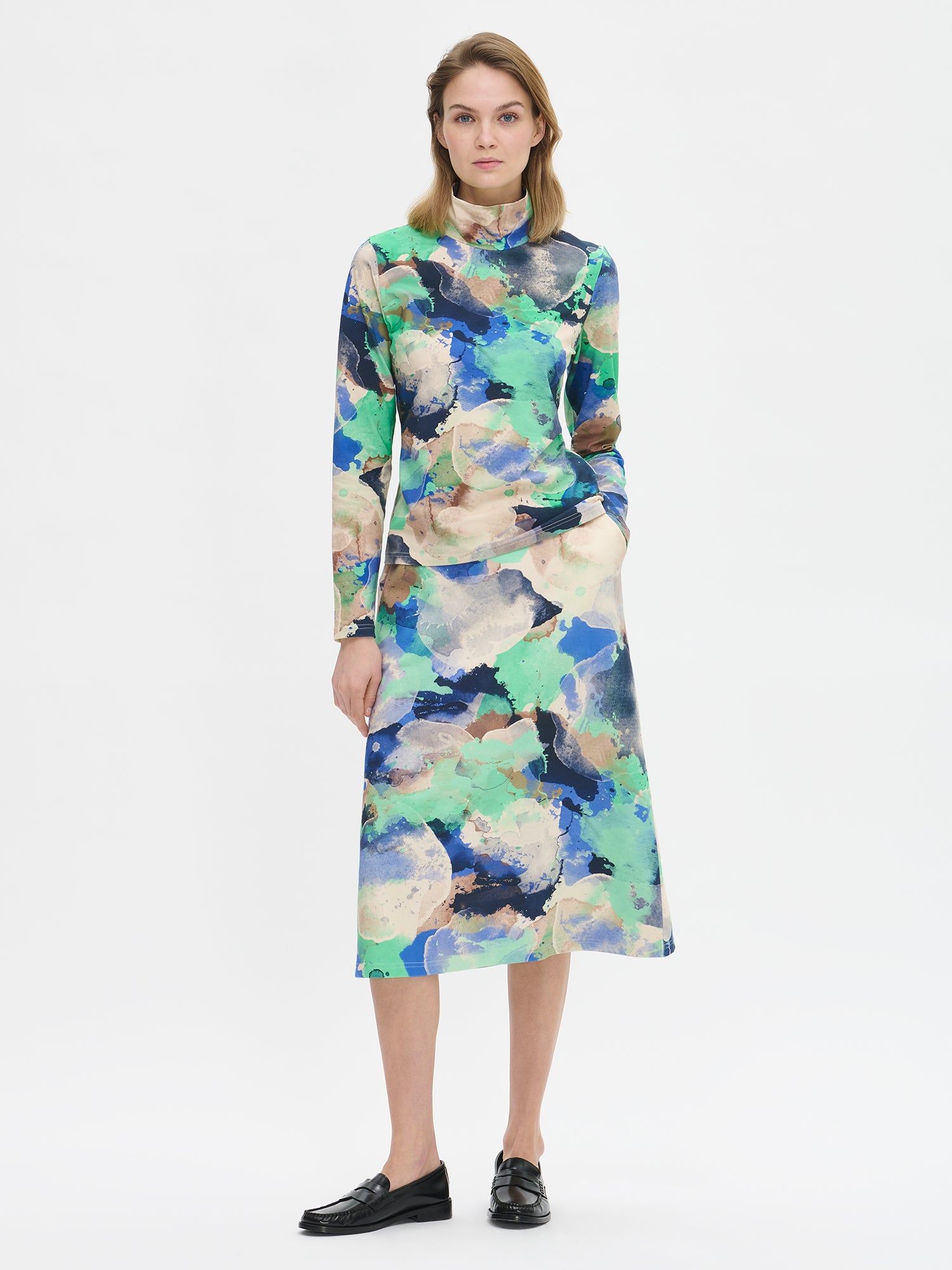 Naisten kuviollinen Sirius-pusero näyttävällä abstraktilla kuosilla ja poolokauluksella. Materiaalina laadukas joustava puuvilla-elastaanineulos. Mallin päällä edestä kuvattuna.