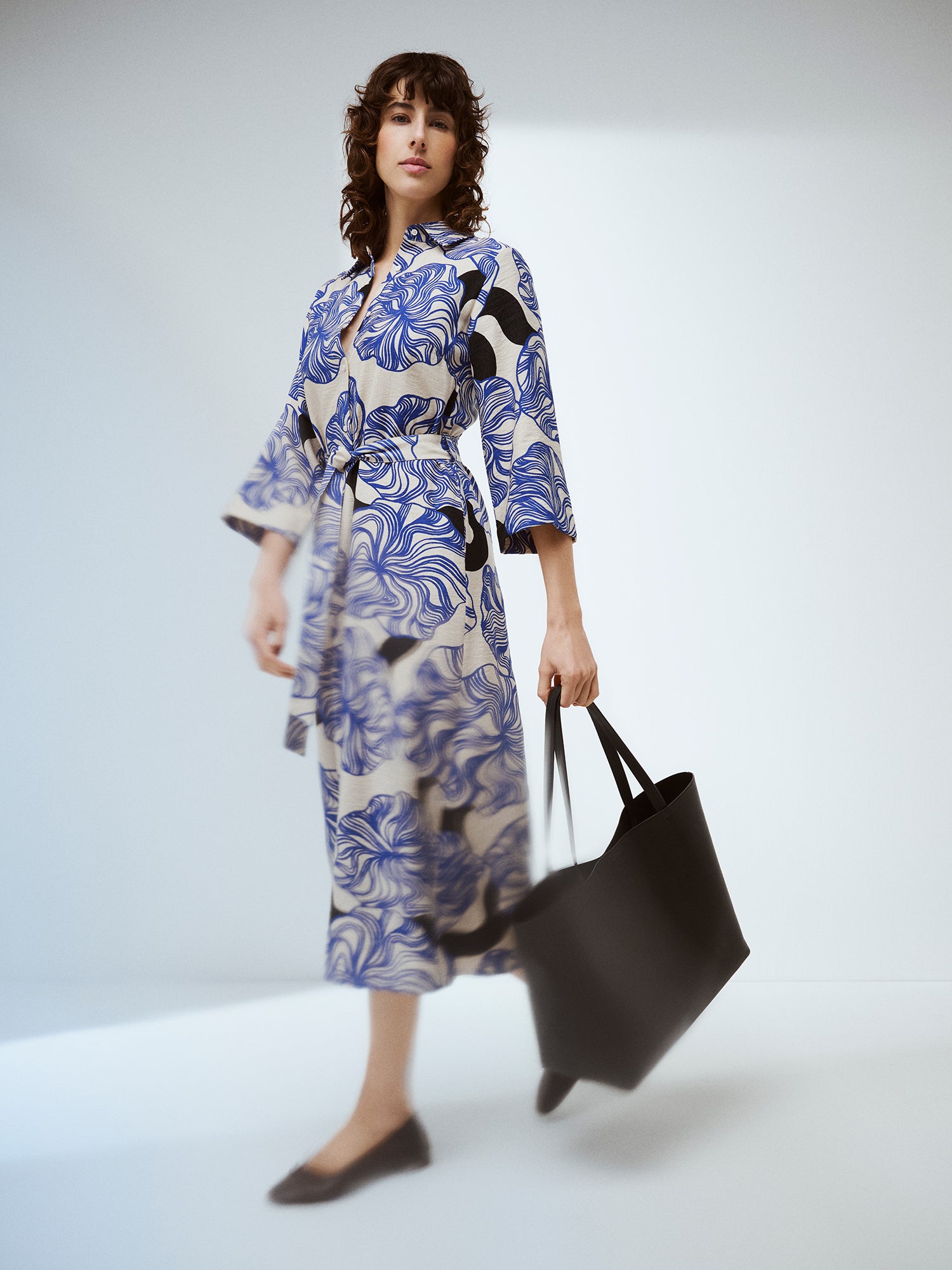 Naisten Kosmo-mekossa yhdistyy pelkistetty klassinen malli ja näyttävä sinisävyinen kuosi. Mekon istuvuus on helppo säätää sopivaksi vyöllä ja siinä on myös käytännölliset taskut. Brändikuvassa mallin päällä mustan Naru Tote laukun kanssa.