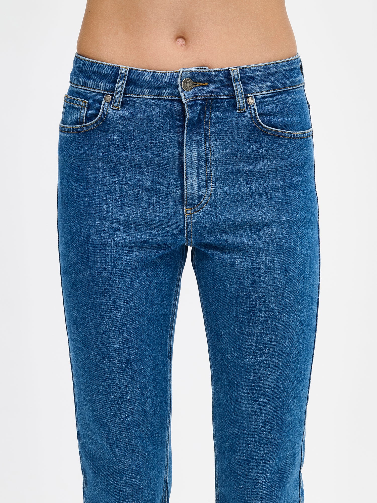 Naisten kapealahkeiset Cropped Kapee-farkut normaalikorkuisella vyötäröllä. Farkuissa on hieman kapenevat ja cropatut lahkeet. Kuvattuna mallin päällä edestä läheltä.