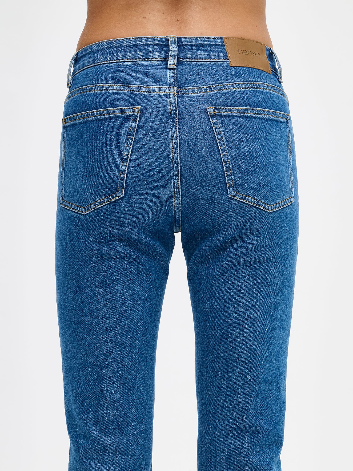 Naisten kapealahkeiset Cropped Kapee-farkut normaalikorkuisella vyötäröllä. Farkuissa on hieman kapenevat ja cropatut lahkeet. Kuvattuna mallin päällä takaa läheltä.