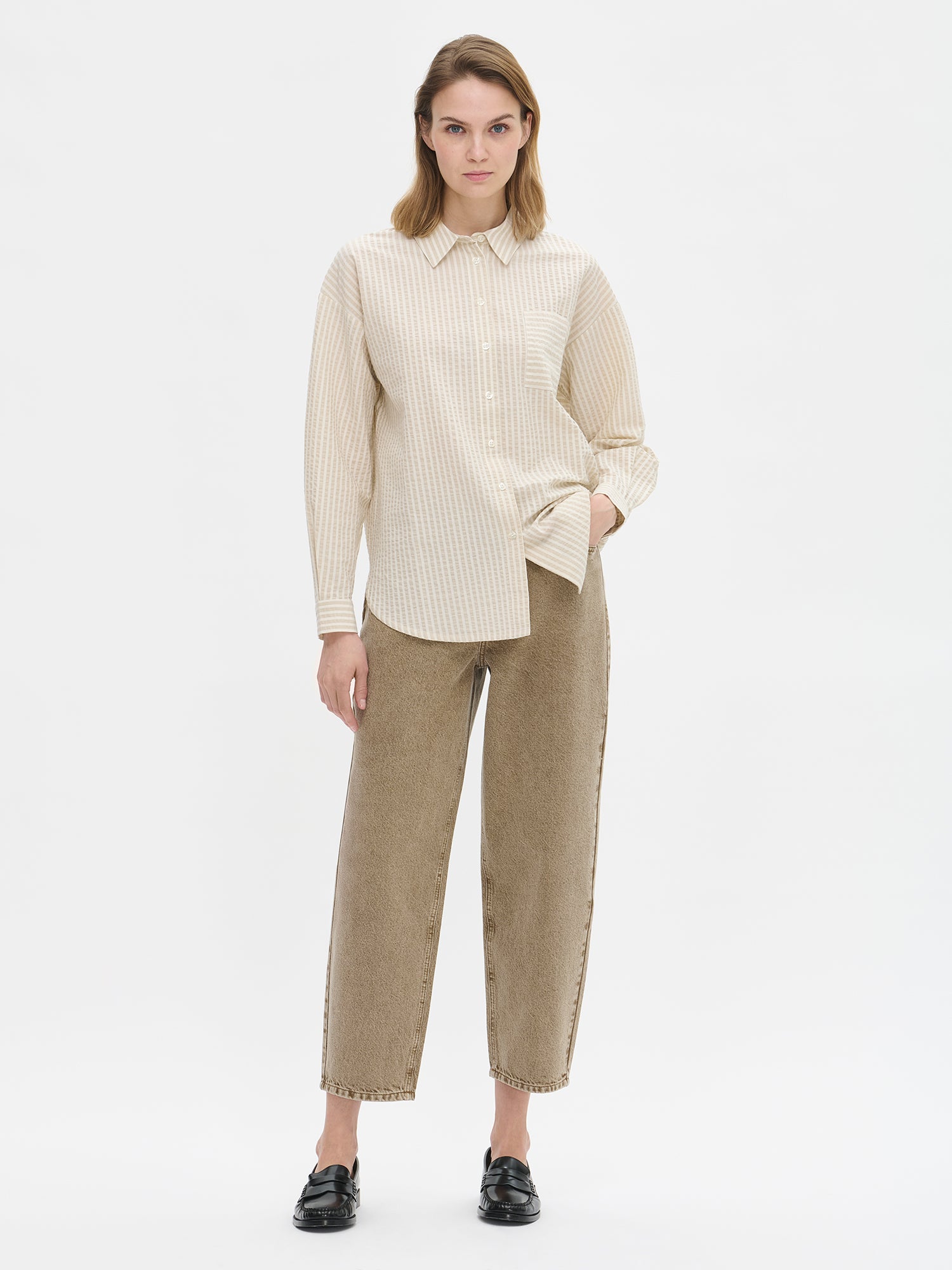 Nanson naisten barrel leg- tyyliset väljät ruskeat Rento-farkut. Farkuissa on normaalikorkuinen vyötärö, edessä vetoketju ja nappikiinnitys. Lahkeet ovat väljät ja kapenevat hieman kohti lahkeensuuta. Mallin päällä paitapuseron kanssa.