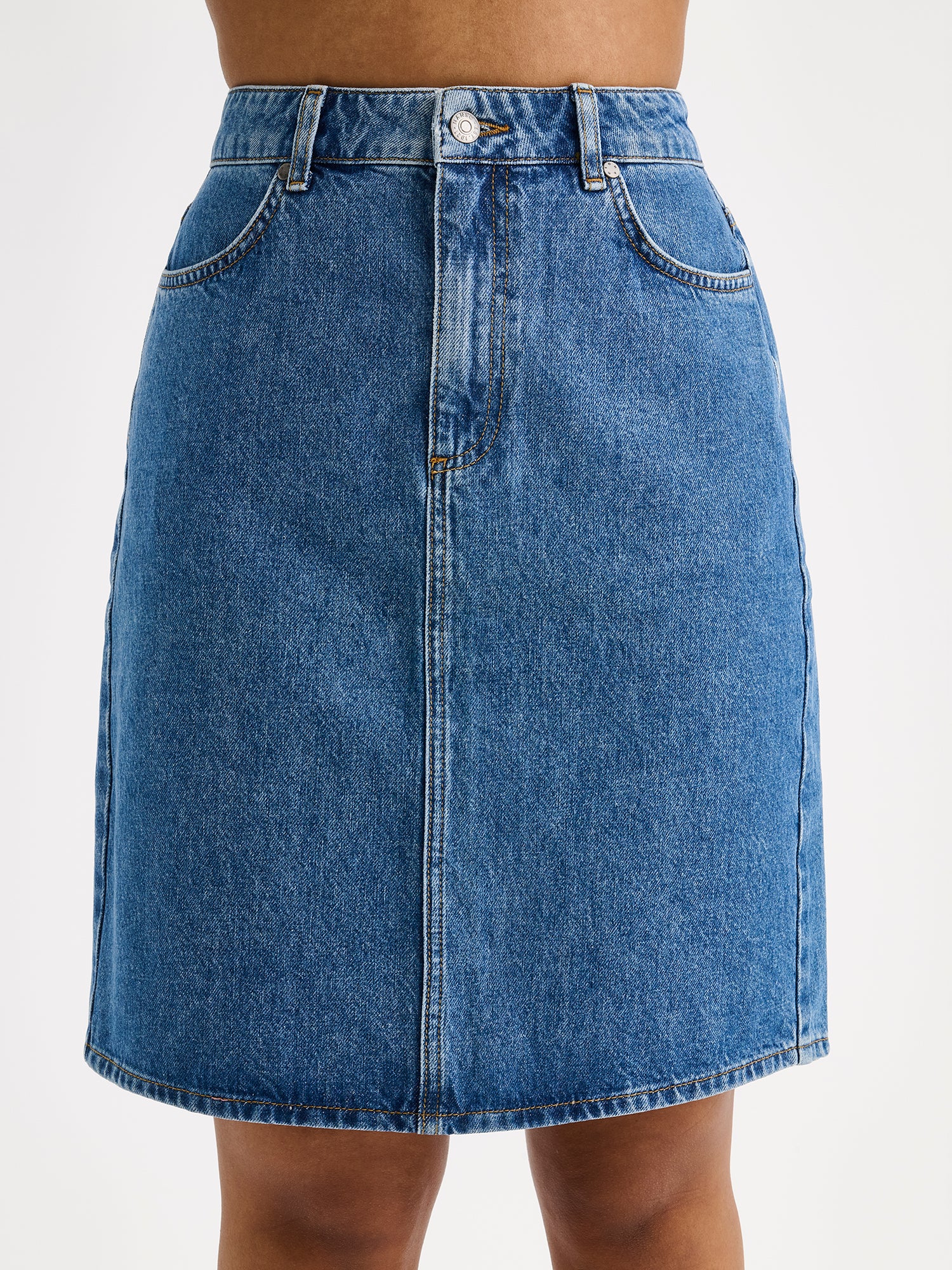 Naisten yhtäaikaa trendikäs ja ajaton Doris-denimhame on monikäyttöinen vaatekaapin peruspilari, joka on helppo yhdistää monenlaisien yläosien kanssa. Lähikuva edestä mallin päällä.