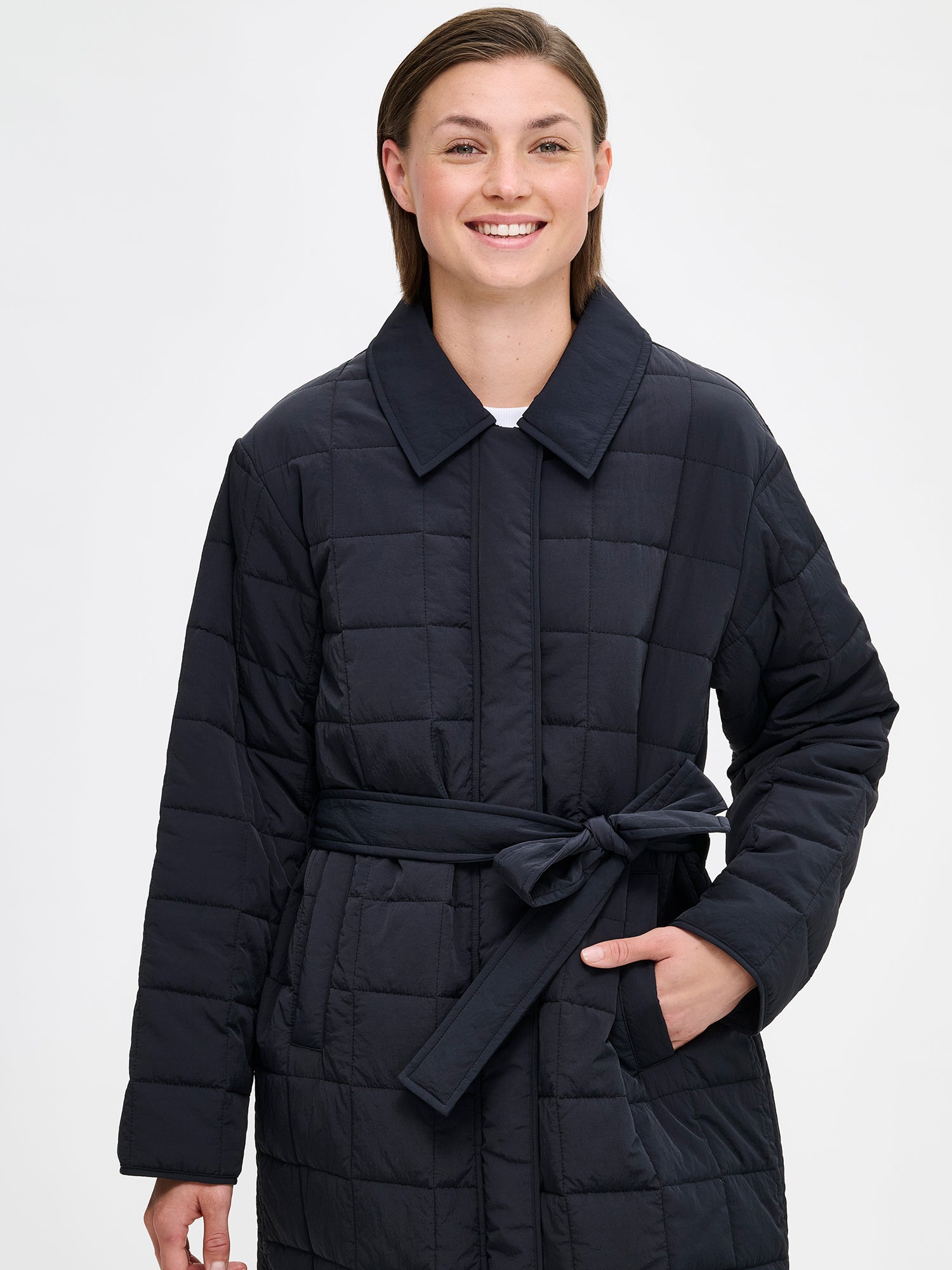 Nanson musta Marje tikkitakki kevyellä vanulla. Takissa on klassiset kaulukset ja edessä nepparikiinnitys. Takin väljyyttä saa kurottua vyöllä ja edessä on listataskut. Kuvassa mallin päällä takki kiinni, läheltä kuvattuna.