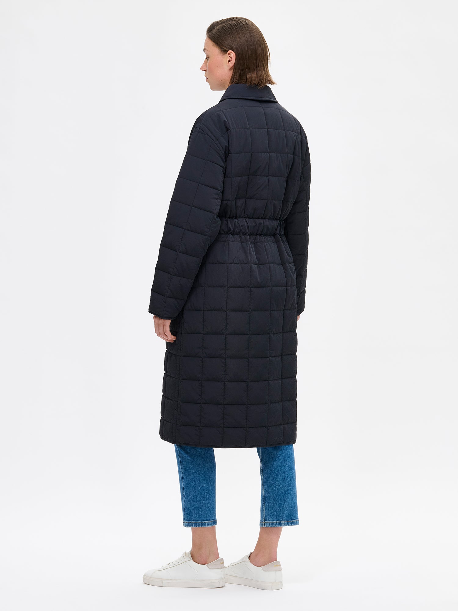 Nanson musta Marje tikkitakki kevyellä vanulla. Takissa on klassiset kaulukset ja edessä nepparikiinnitys. Takin väljyyttä saa kurottua vyöllä ja edessä on listataskut. Kuvassa mallin päällä takaa kuvattuna.