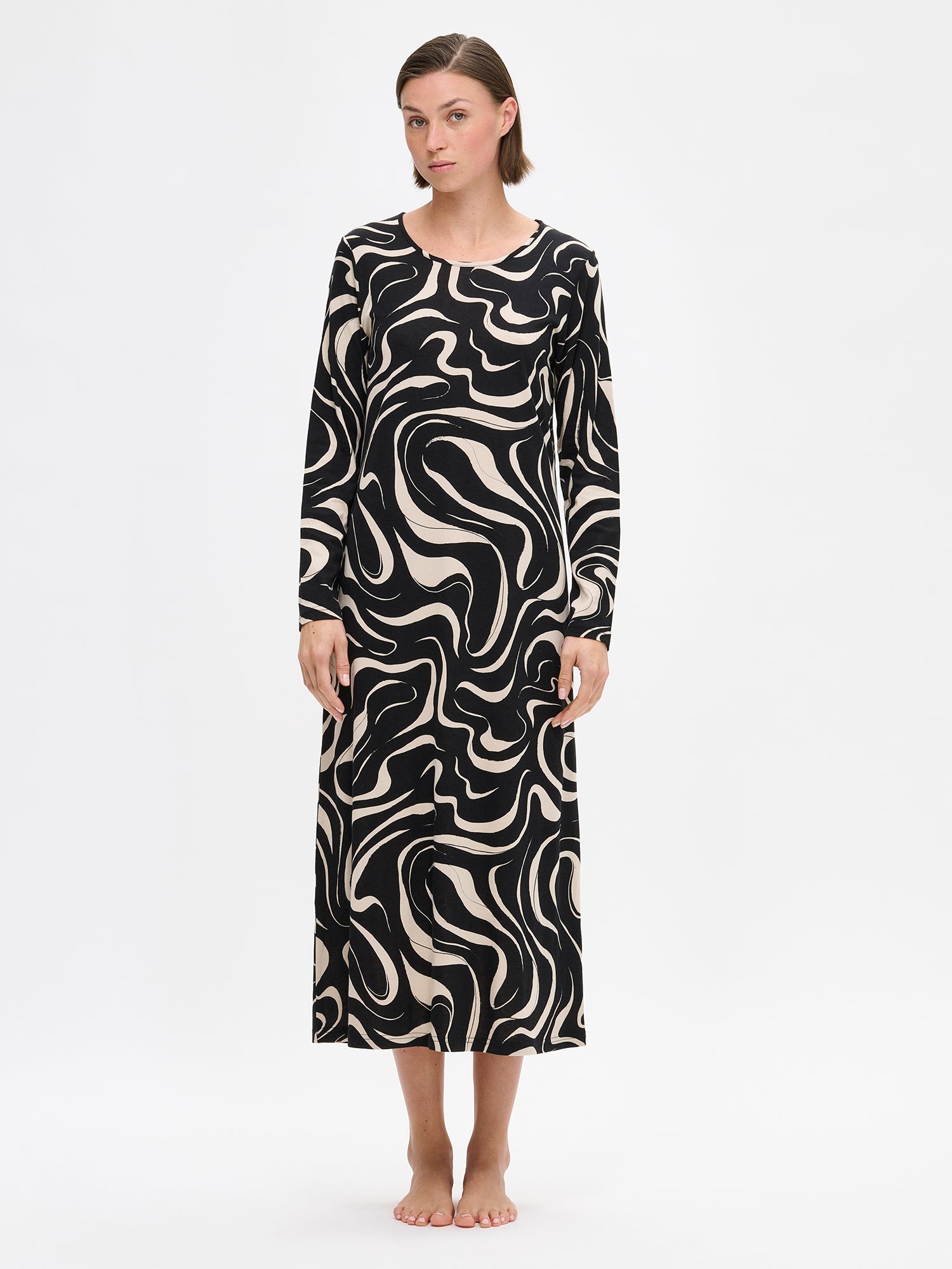 Naisten beige kuosillinen Vesi-yöpaita pitkillä hihoilla ja pyöreällä pääntiellä. Materiaali on laadukasta, iholla miellyttävän pehmeältä tuntuvaa ja helppohoitoista puuvilla-modaalia. Kuvassa mallin päällä edestä.