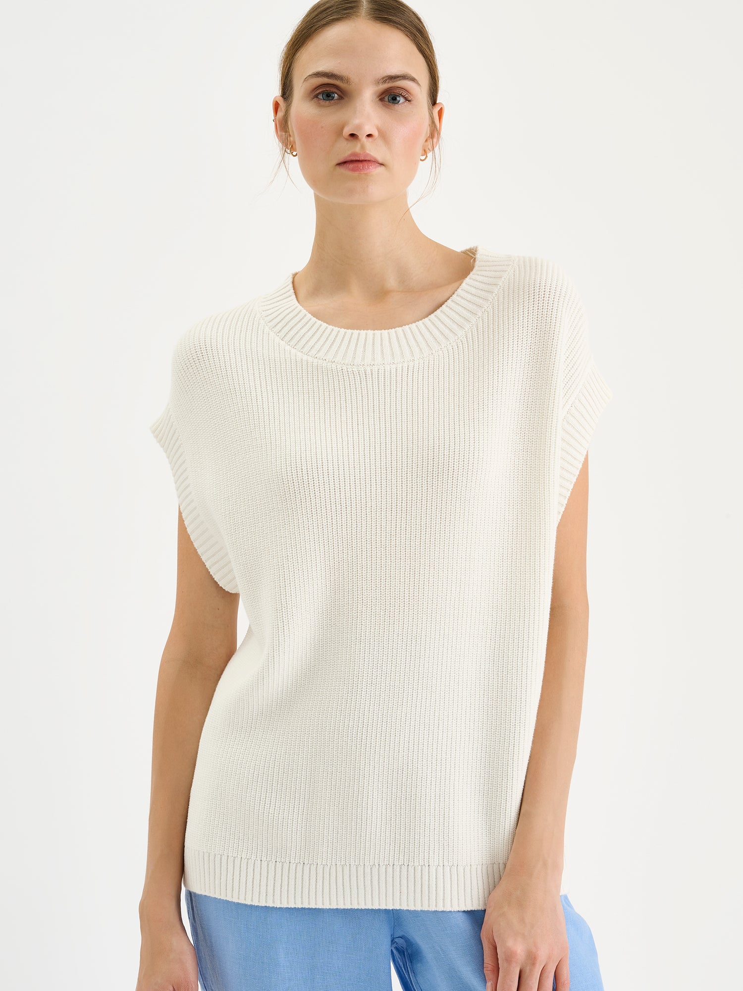 Nanson naisten tyylikäs luonnonvalkoinen puuvillainen Kaveri-neuleliivi mallin päällä sinisten pellavahousujen kanssa lähikuvassa