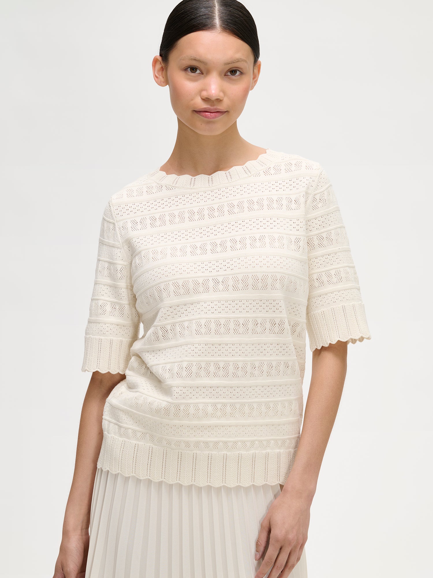 Nanson naisten valkoinen Koru-neulepaita puolipitkillä hihoilla pitsineuloksesta mallin päällä lähikuvassa.
