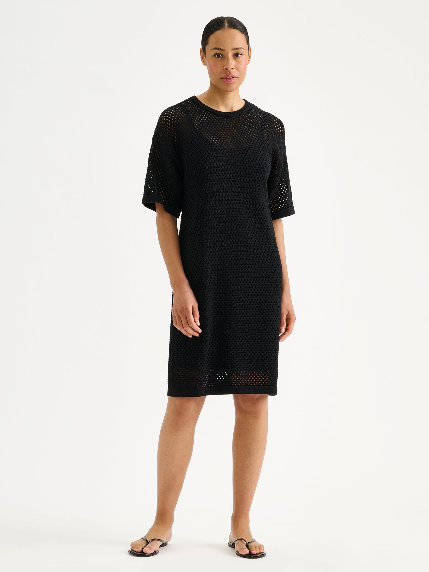 Nanson naisten trendikäs musta Aure -reikäneulemekko mallin päällä sandaalien kanssa