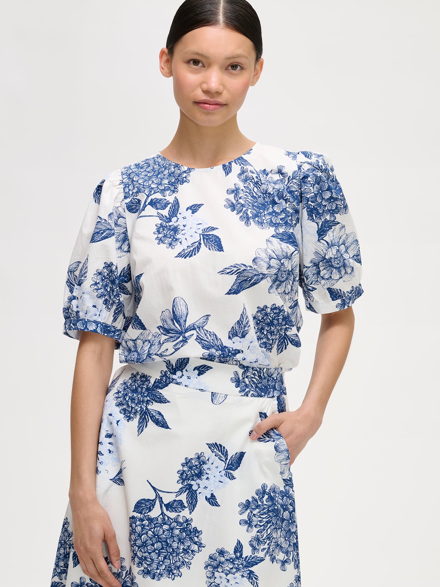 Naisten kuosillinen sini-valkoinen Palatsi-pusero herkällä kukkakuosilla mallin päällä Palatsi-hameen kanssa lähikuvassa