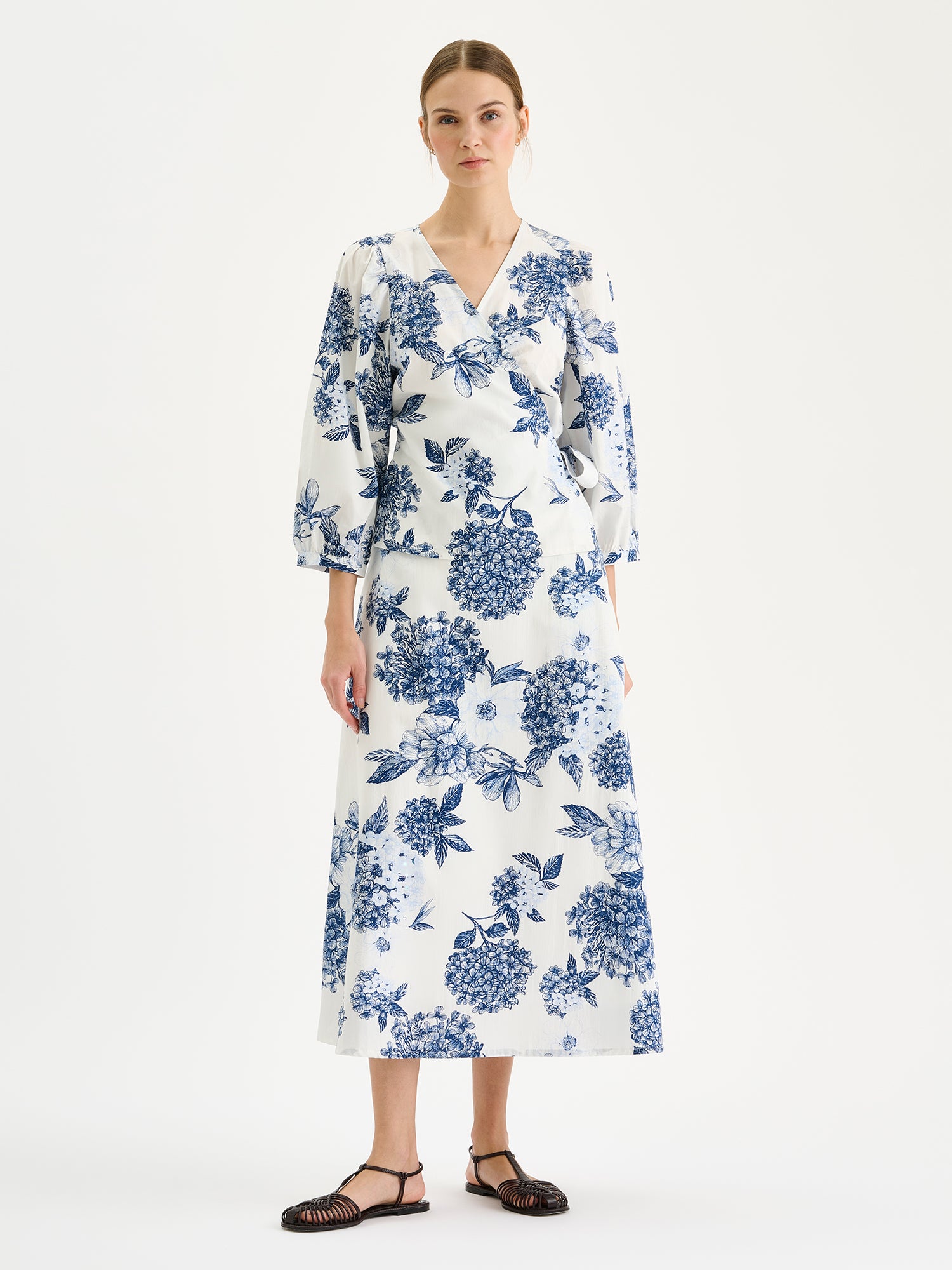 Naisten hurmaava kuosillinen sinivalkoinen Palatsi-kietaisupusero mallin päällä saman sarjan hameen kanssa.