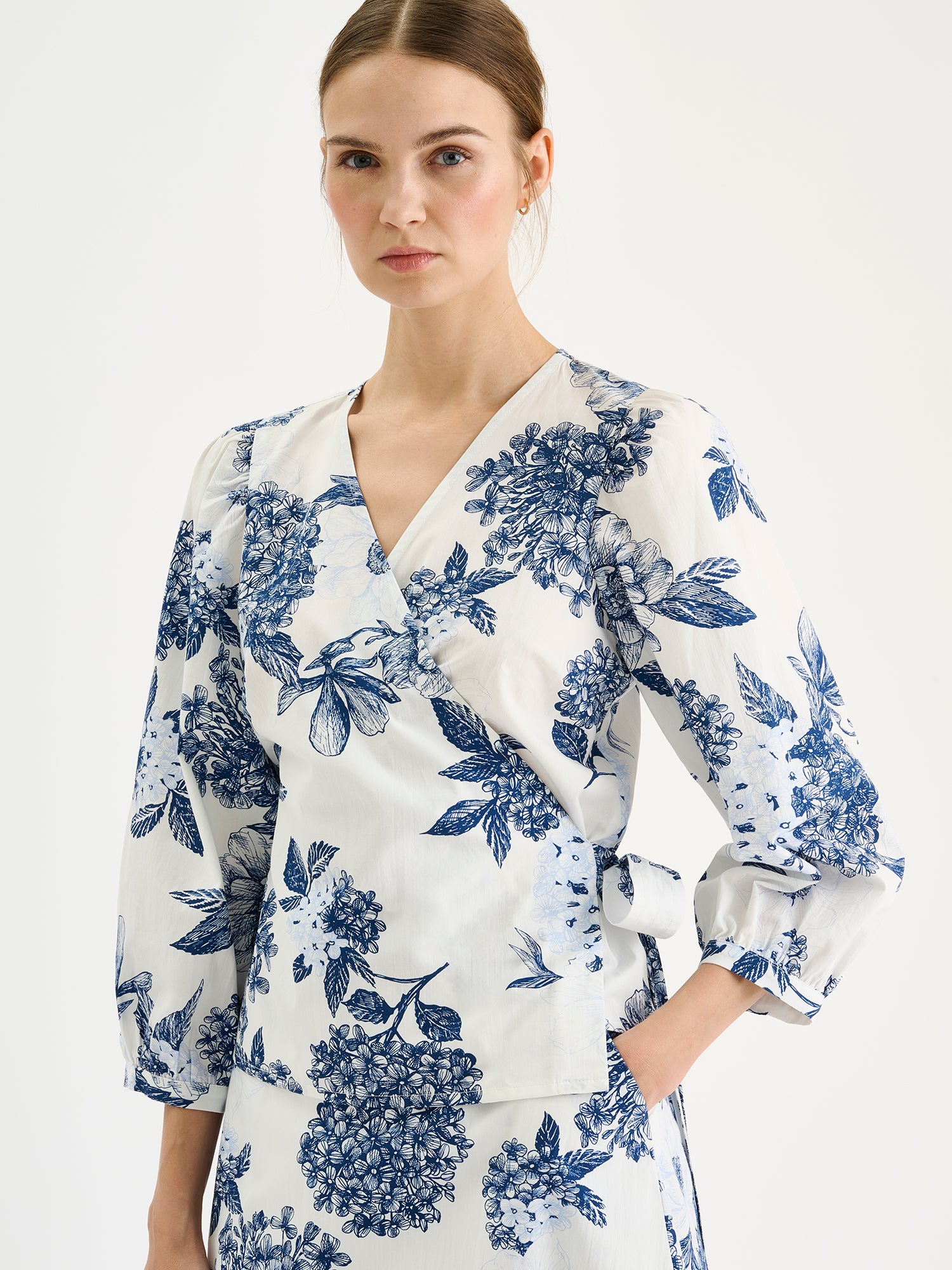 Naisten hurmaava kuosillinen sinivalkoinen Palatsi-kietaisupusero mallin päällä saman sarjan hameen kanssa lähikuvassa.