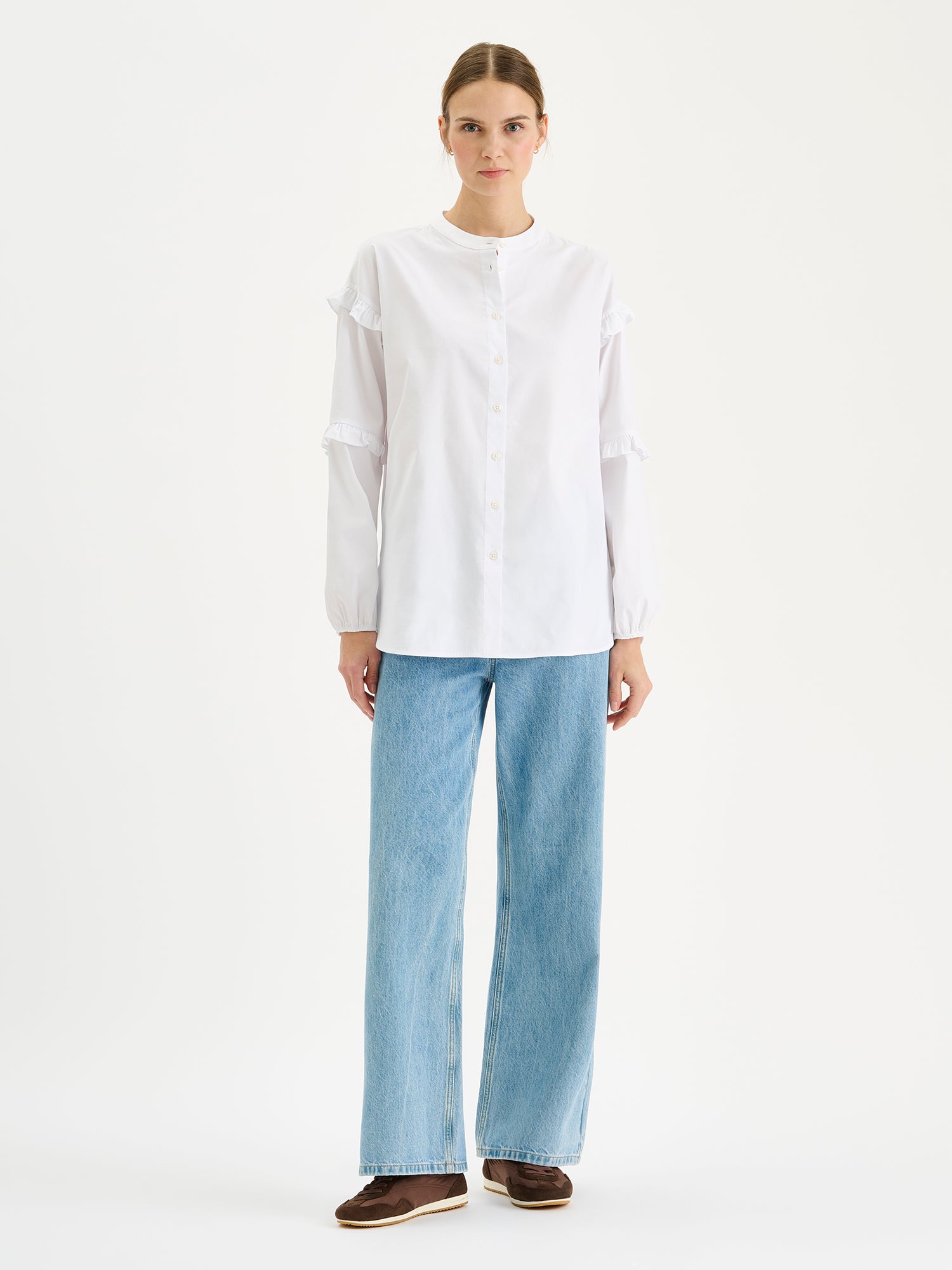 Naisten raikas valkoinen Katri-paitapusero, jossa on kauniit frillayksityiskohdat hihoissa. Kuvassa mallin päällä farkkujen kanssa.