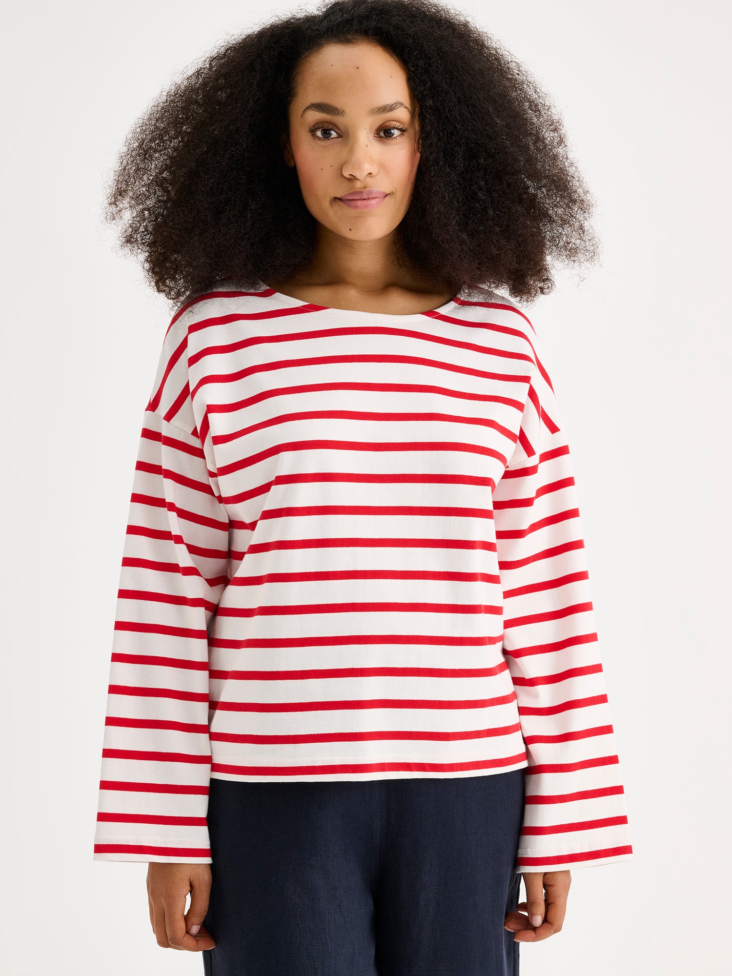 Naisten puna-valko-raidallinen ja ihanan rennon mallinen Breton-pusero mallin päällä pellavahousujen kanssa lähikuvassa