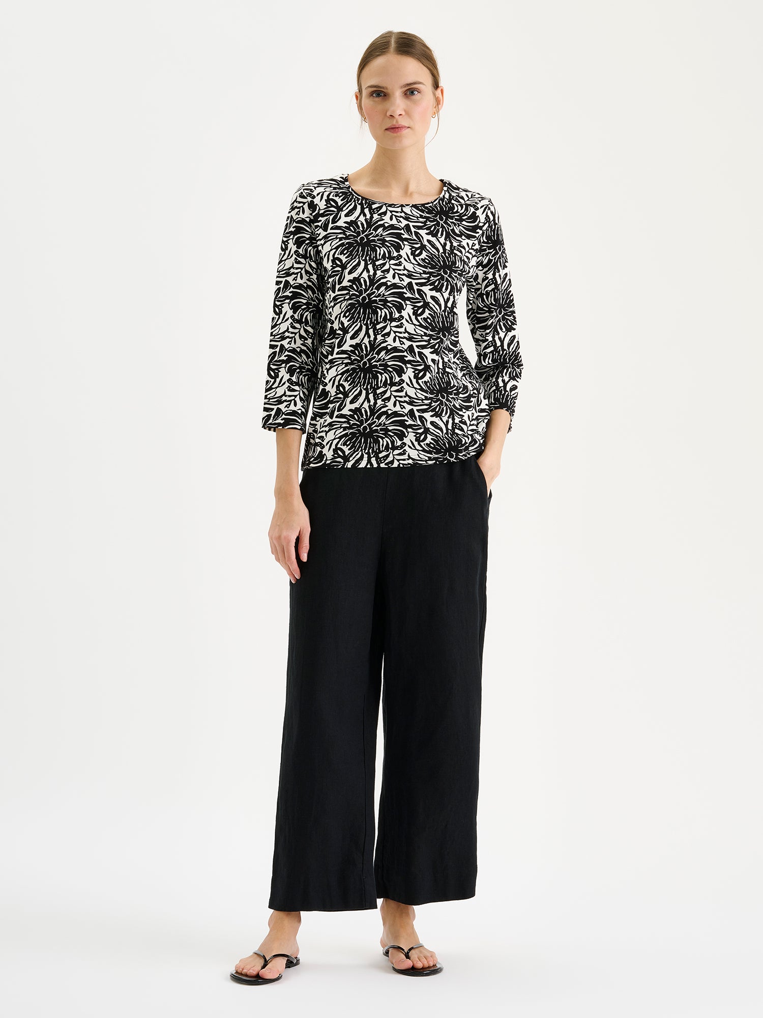 Nanson naisten kuosillinen mustavalkoinen Safiiri-trikoopusero mallin päällä mustien housujen kanssa.