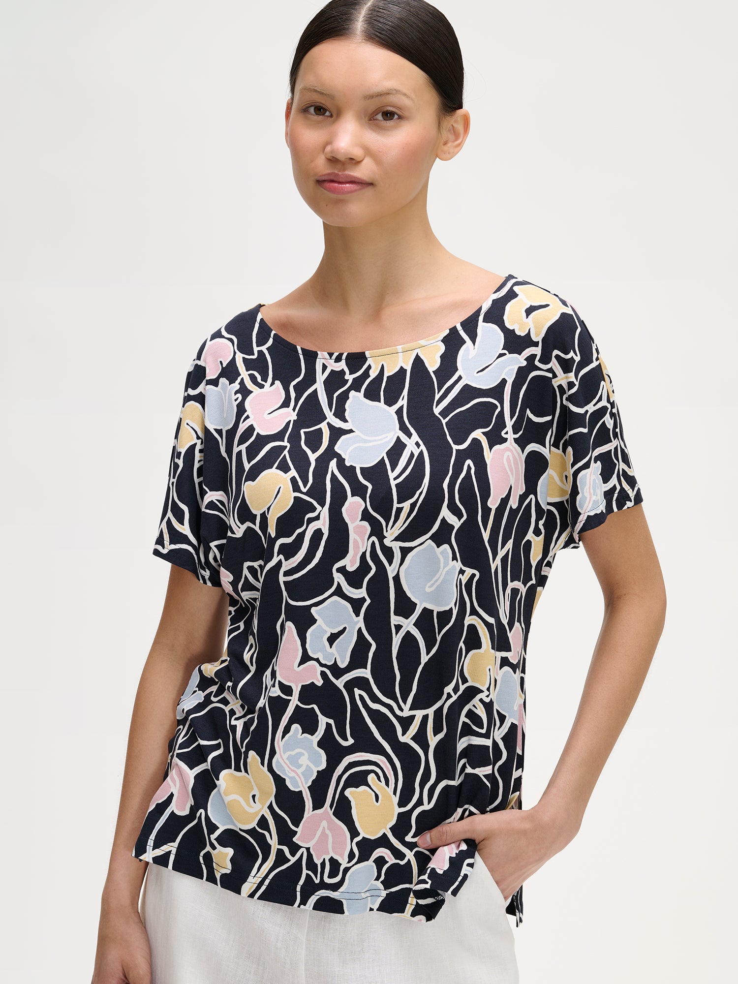 Nanson naisten kuosillinen holkkihihainen Iiris-pusero mallin päällä valkoisten pellavahousujen kanssa lähikuvassa.