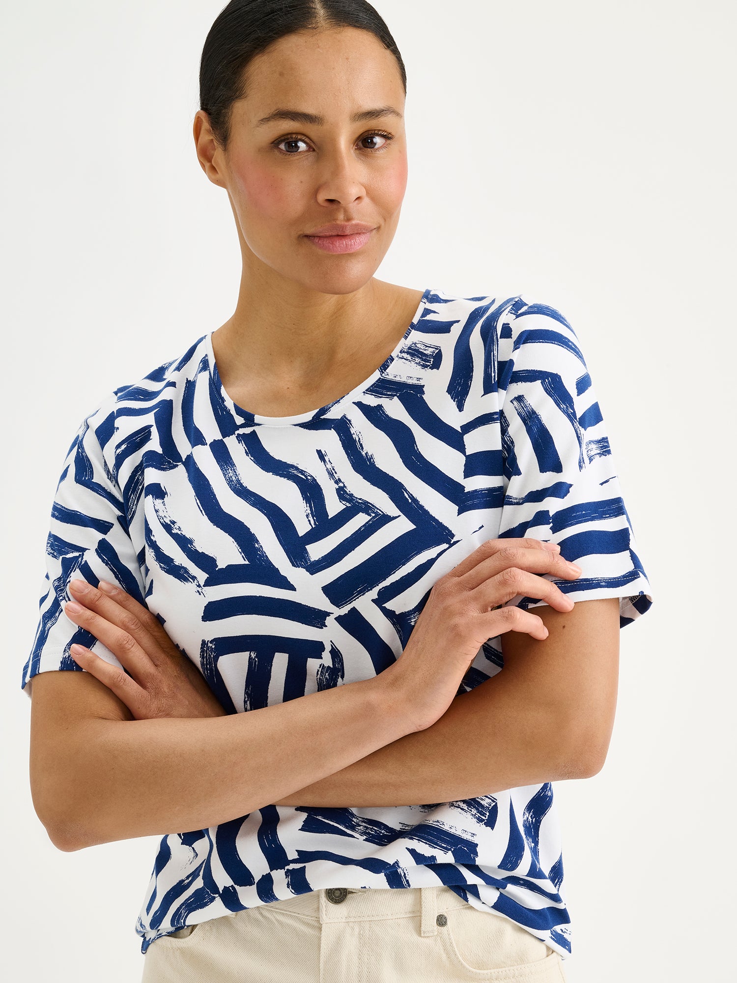 Naisten laadukas kuosillinen Seilori-t-paita, jossa on raikas sinivalkoinen kuosi mallin päällä vaaleiden farkkujen kanssa lähikuvassa.