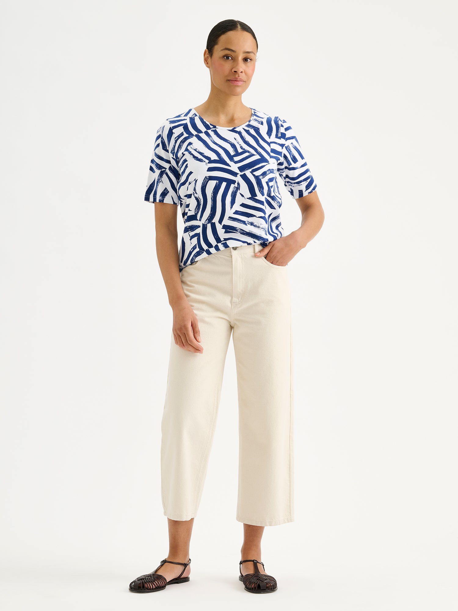 Naisten laadukas kuosillinen Seilori-t-paita, jossa on raikas sinivalkoinen kuosi mallin päällä vaaleiden farkkujen kanssa.