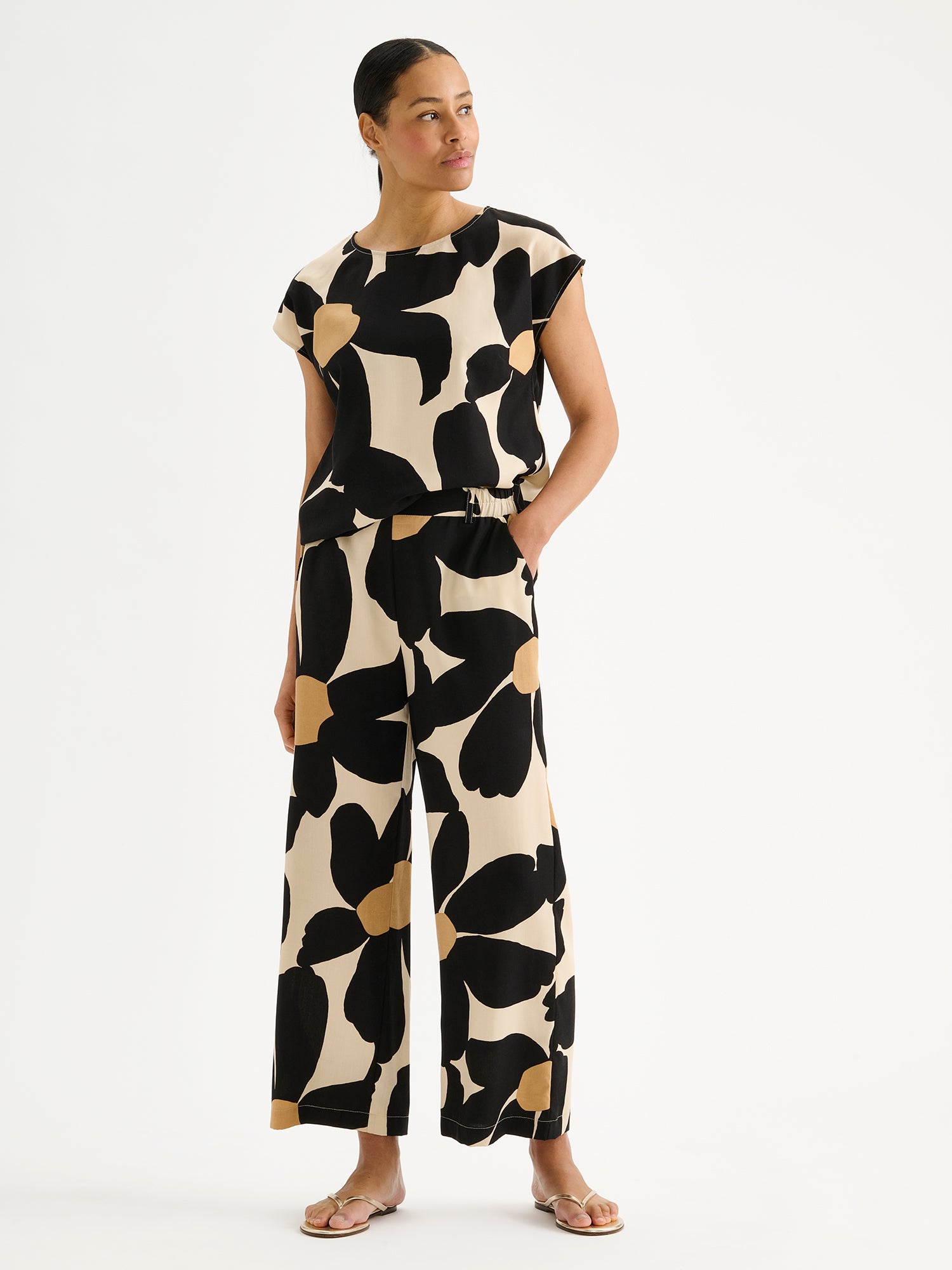 Nanson naisten mukavan rennot, leveälahkeiset beige-mustat Rosi-housut mallin päällä saman sarjan puseron kanssa.