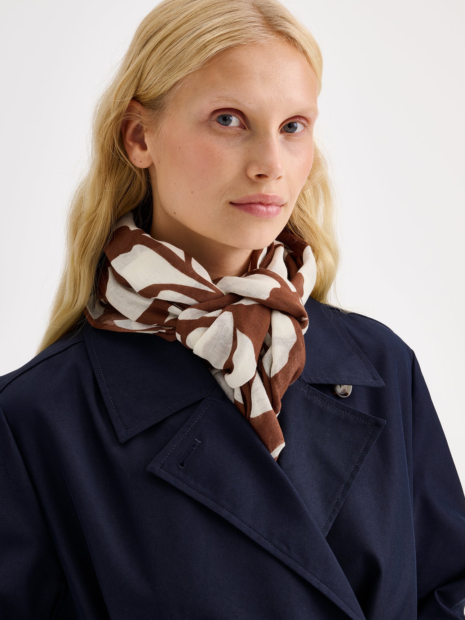 Naisten tyylikäs kuviollinen ruskea-valkoinen Palsta-huivi ihanan kevyestä ja hengittävästä viskoosi-pellava-sekoitteesta mallin päällä sinisen trenssin kanssa