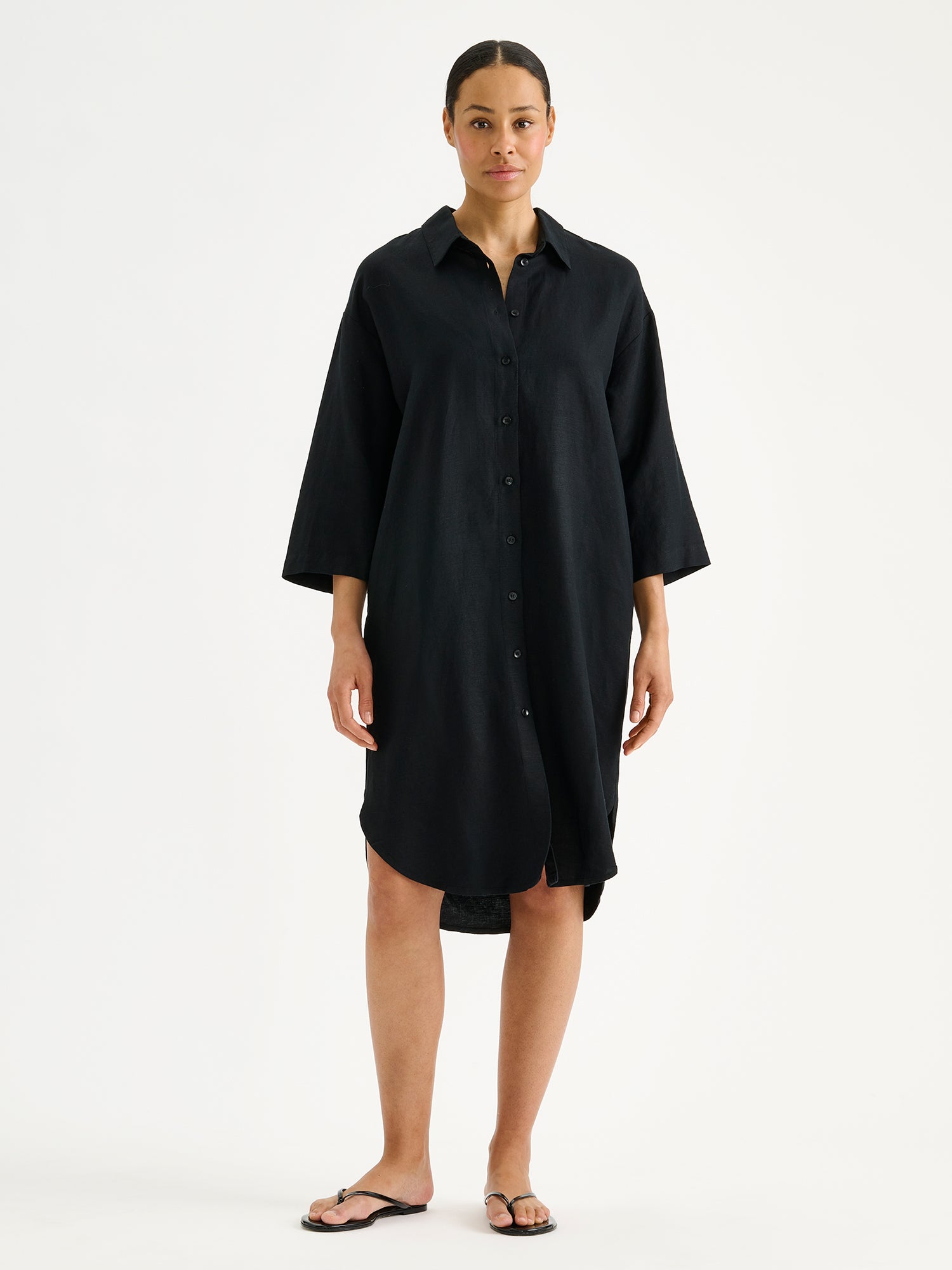 Nanson naisten musta ja mukavan rennon mallinen Irene-paitamekko mallin päällä sandaalien kanssa.