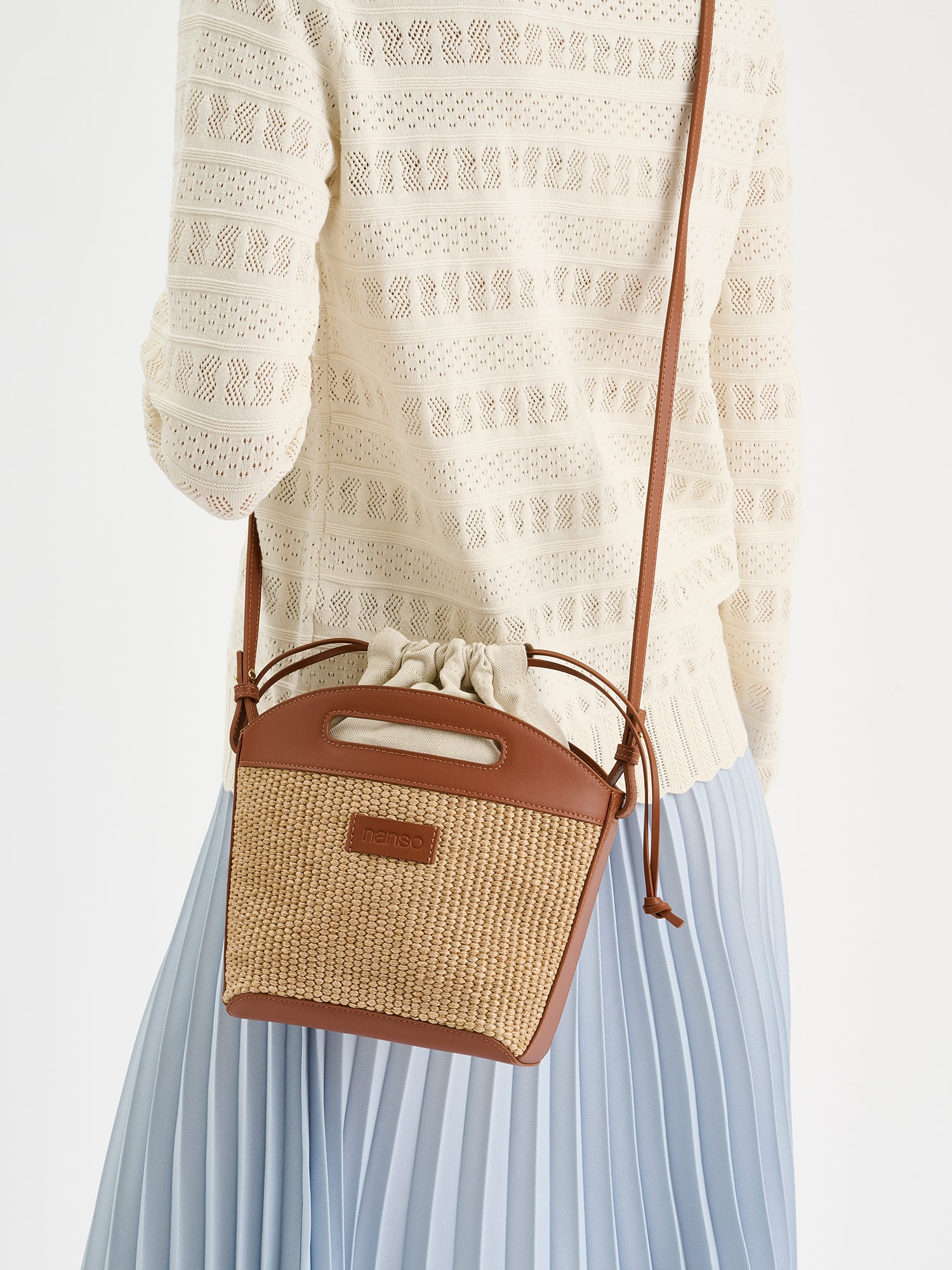 Tyylikäs Kori-laukku kestävästä olkipunosta muistuttavasta materiaalista. Laukussa on puuvillavuori ja nahkaiset kantohihnat ja pohja. Kuvattuna mallin päällä.