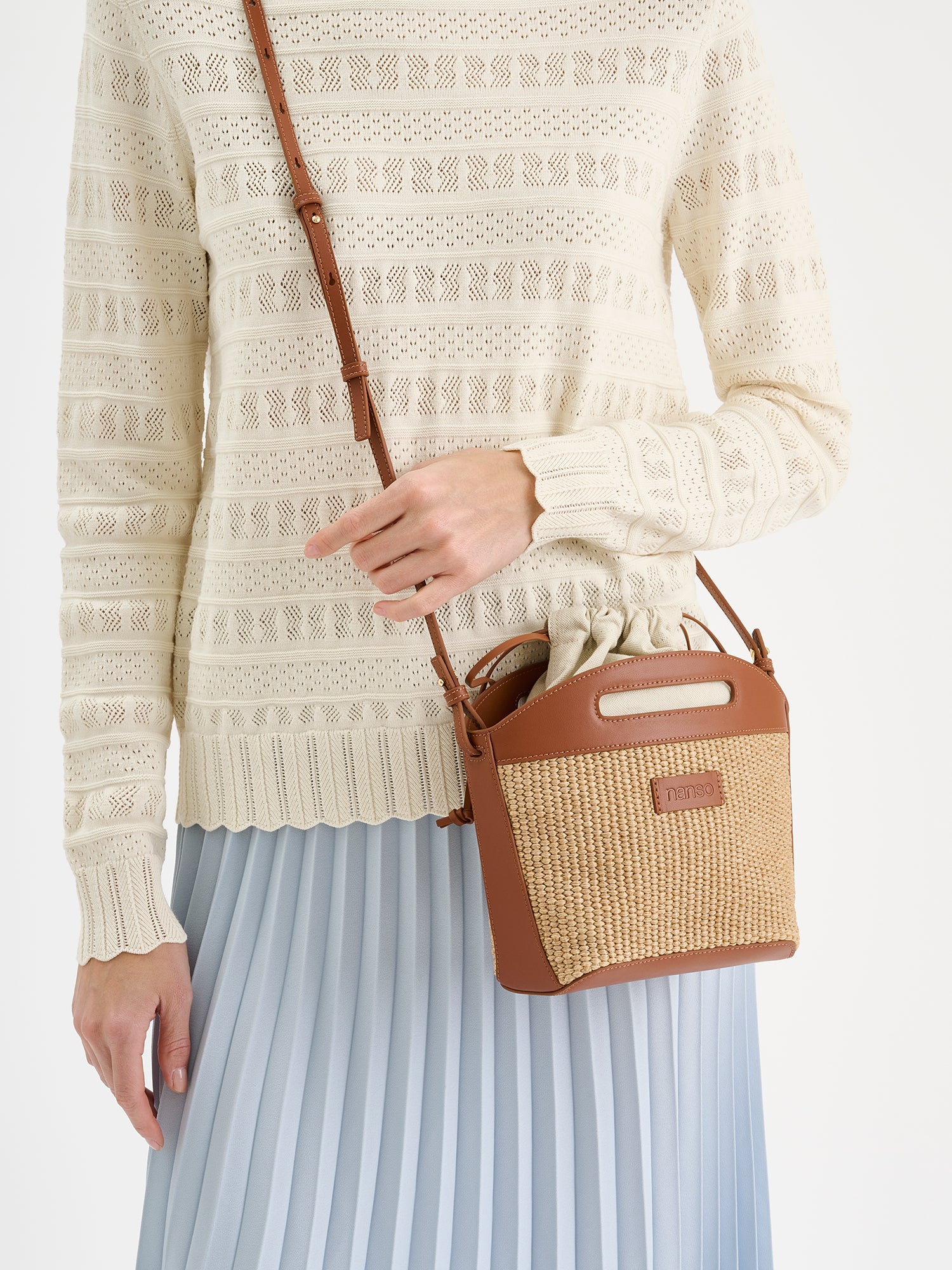 Tyylikäs Kori-laukku kestävästä olkipunosta muistuttavasta materiaalista. Laukussa on puuvillavuori ja nahkaiset kantohihnat ja pohja. Kuvattuna mallin päällä.